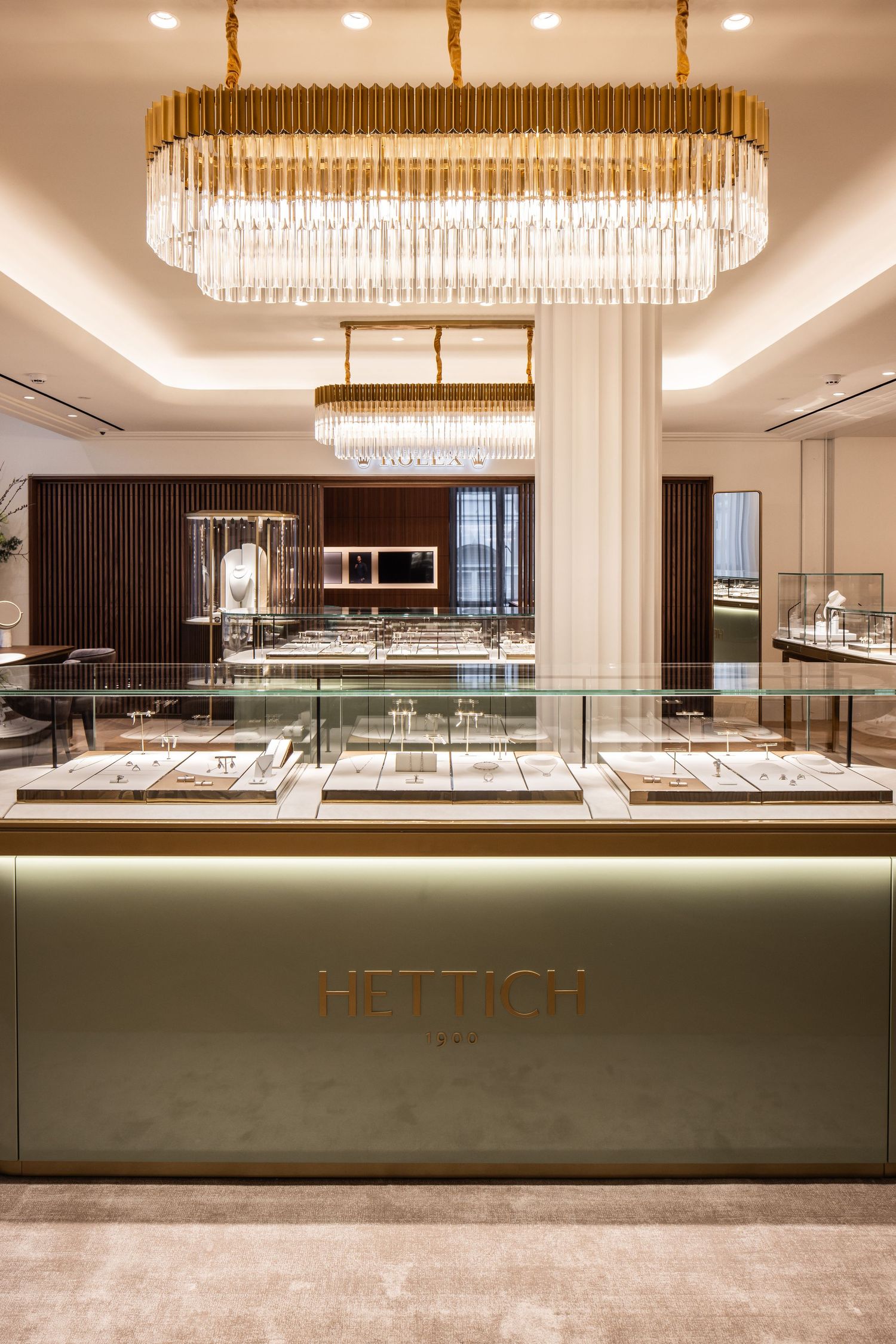 Luxurious retail interior featuring crystal chandeliers and gold accents with modern display cases.