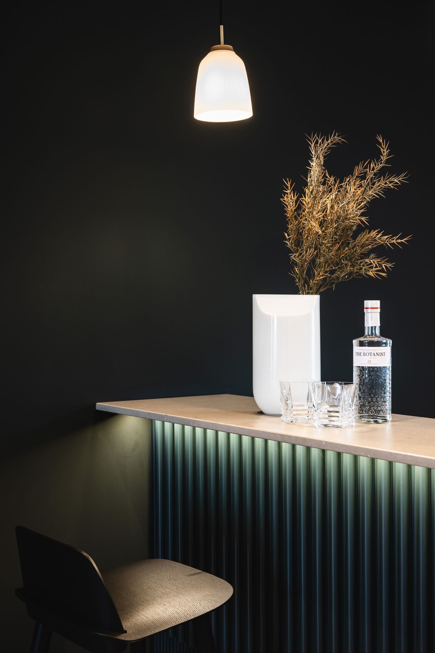 Dark modern bar counter with pendant lighting and decorative glassware display.