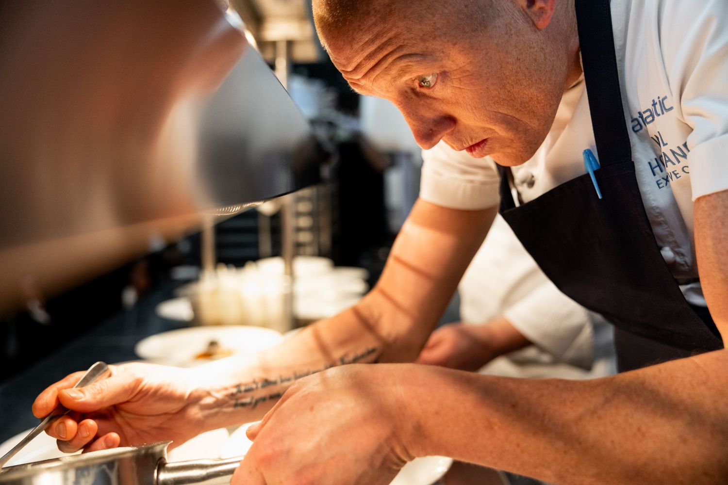 Chef carefully plating dishes with precision in professional kitchen setting.