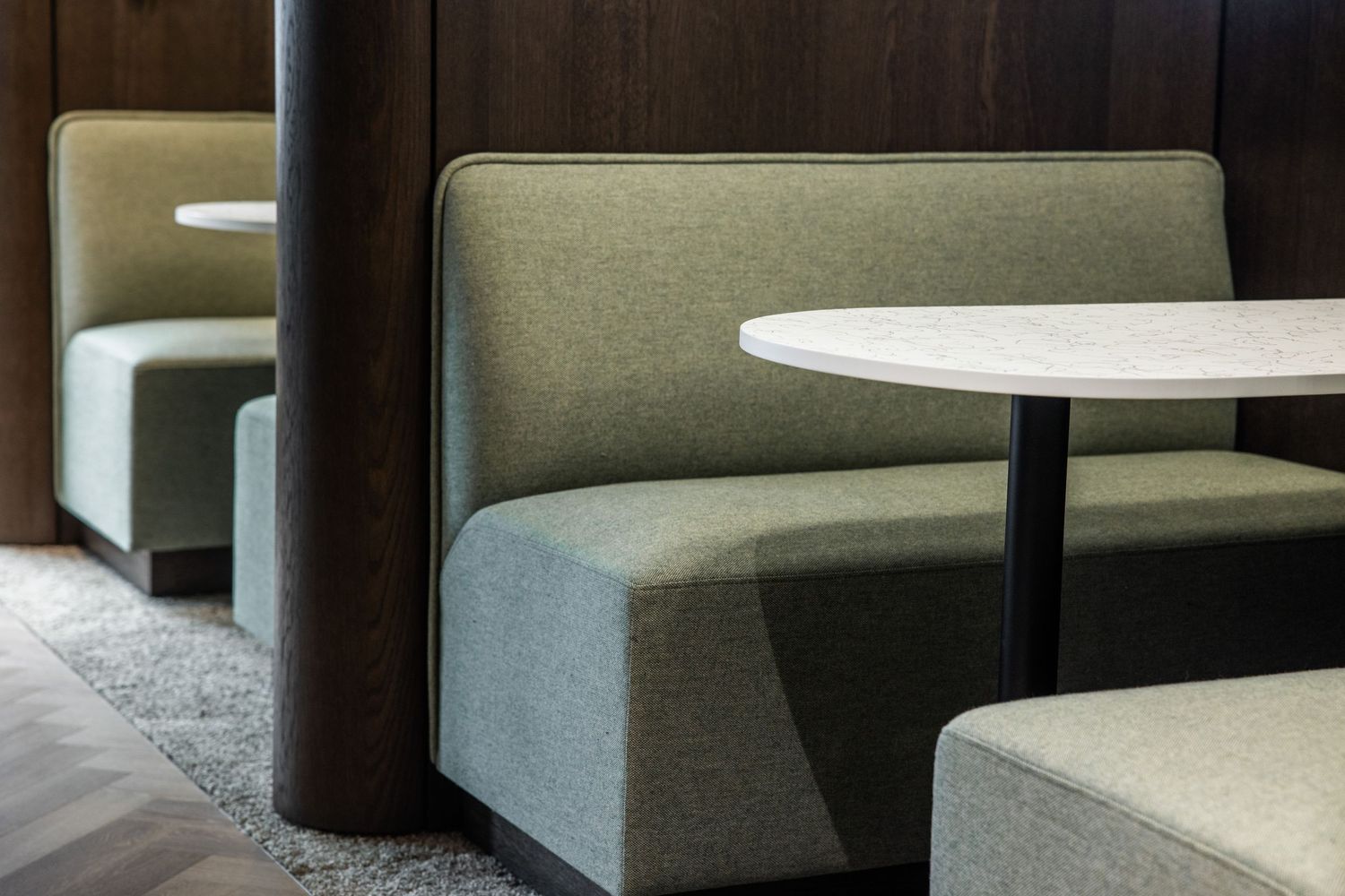 Contemporary office seating area with plush grey upholstered benches and modern design elements.