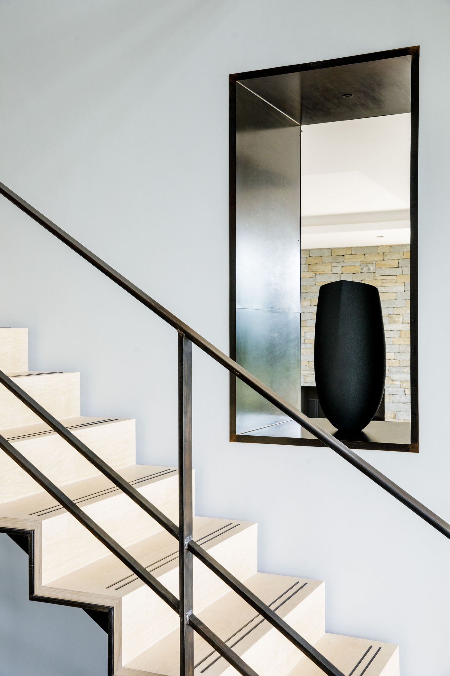 Minimalist white staircase with black metal railings and geometric window details.