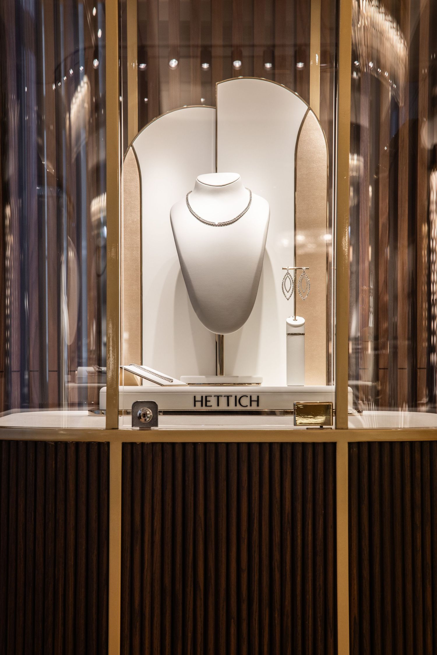 Elegant jewelry display cases with illuminated necklace presentations and wood slat details.