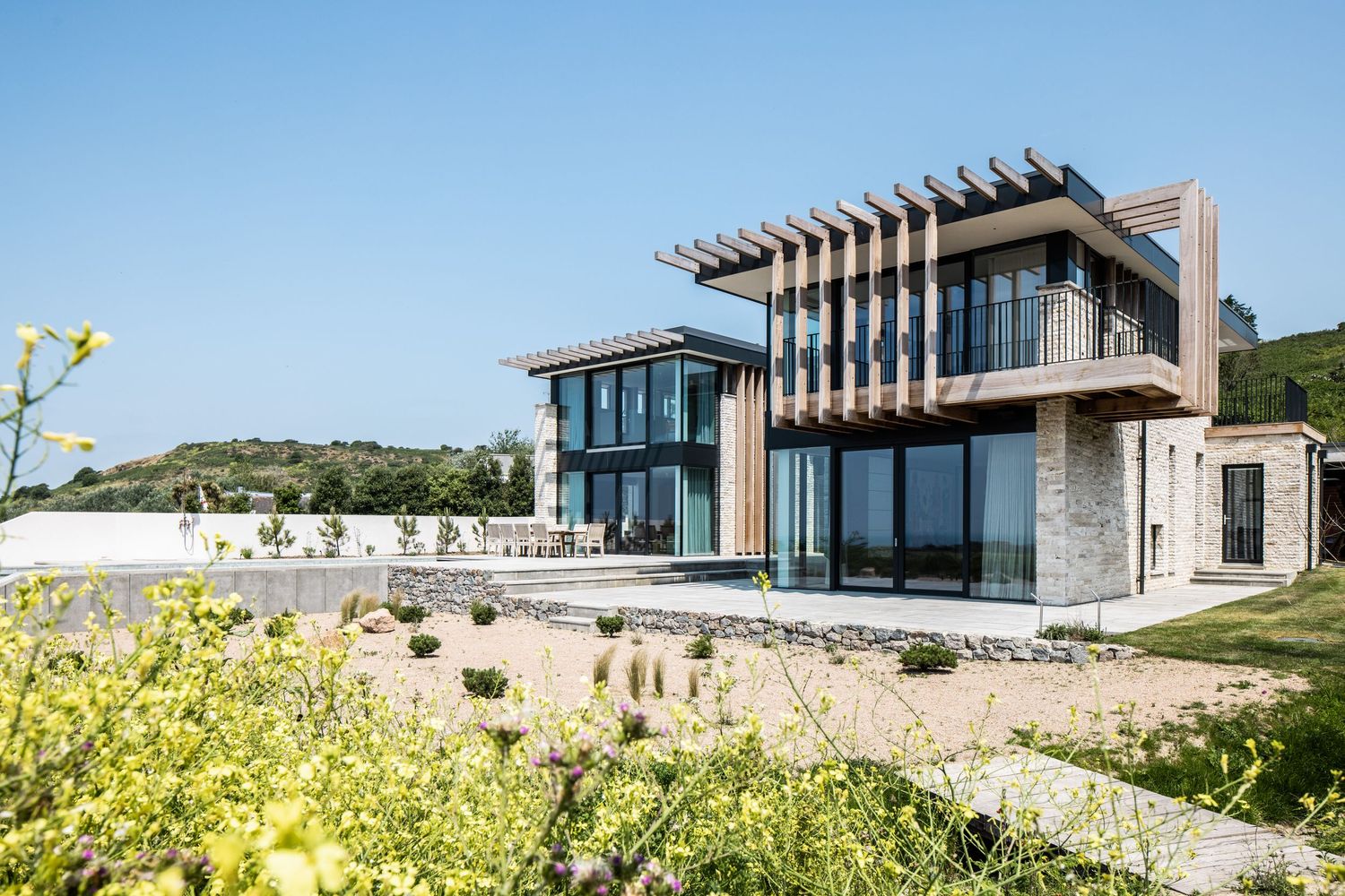 Modern architectural building with glass facades set against blue sky and natural landscape.