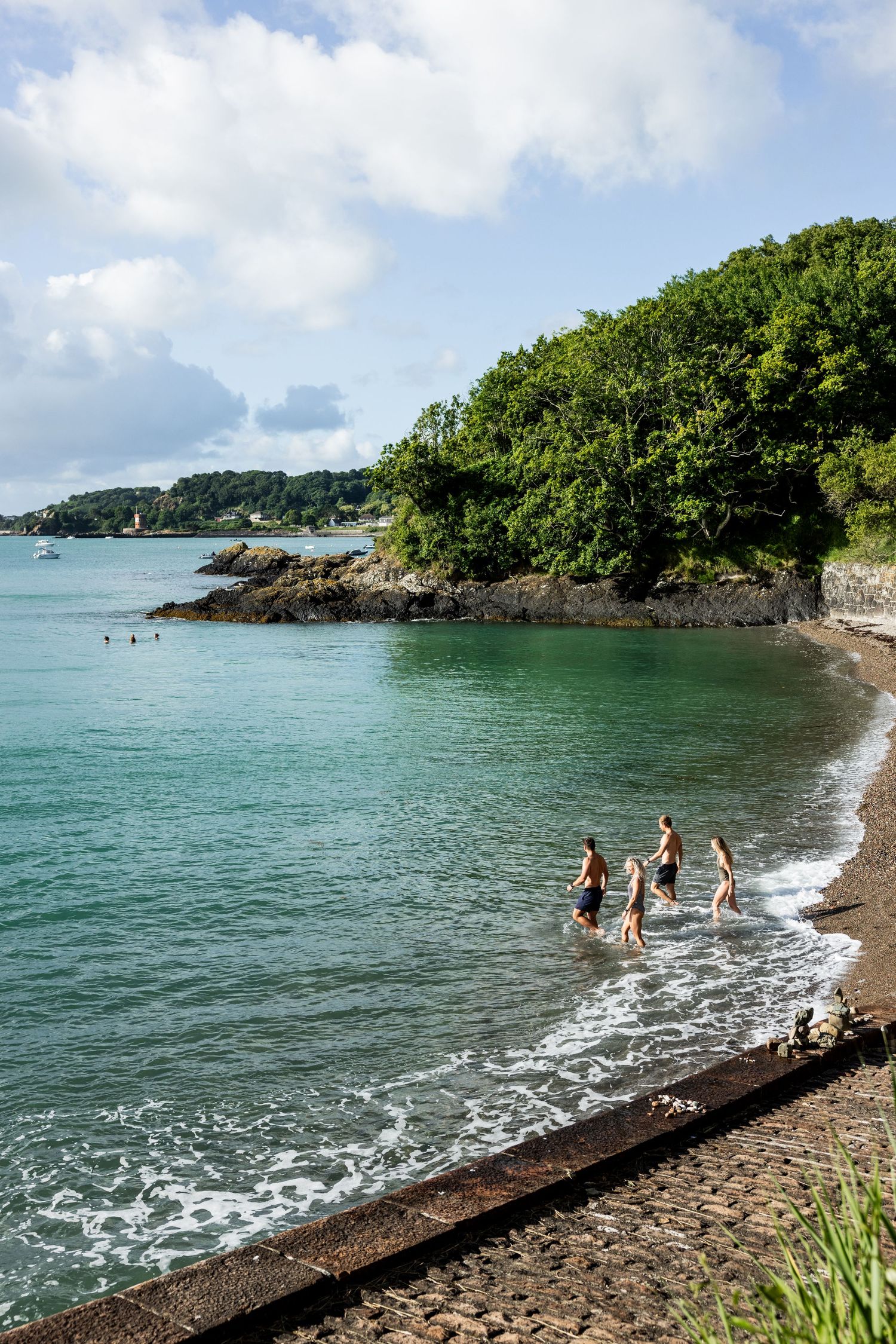 Scenic coastal view with rocky beach and turquoise waters under cloudy sky.