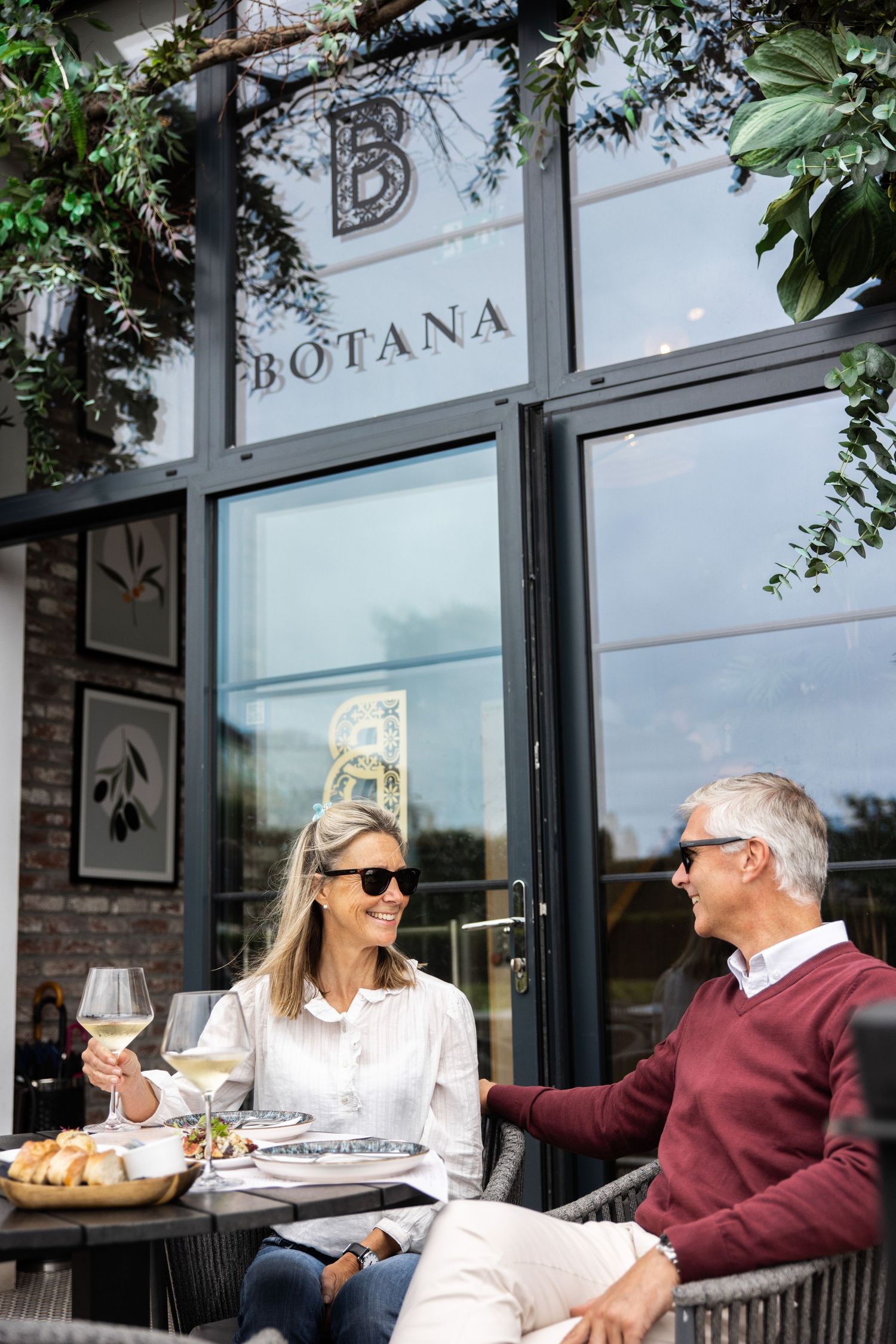 Couple enjoying white wine on the patio of Botana restaurant on a sunny day.