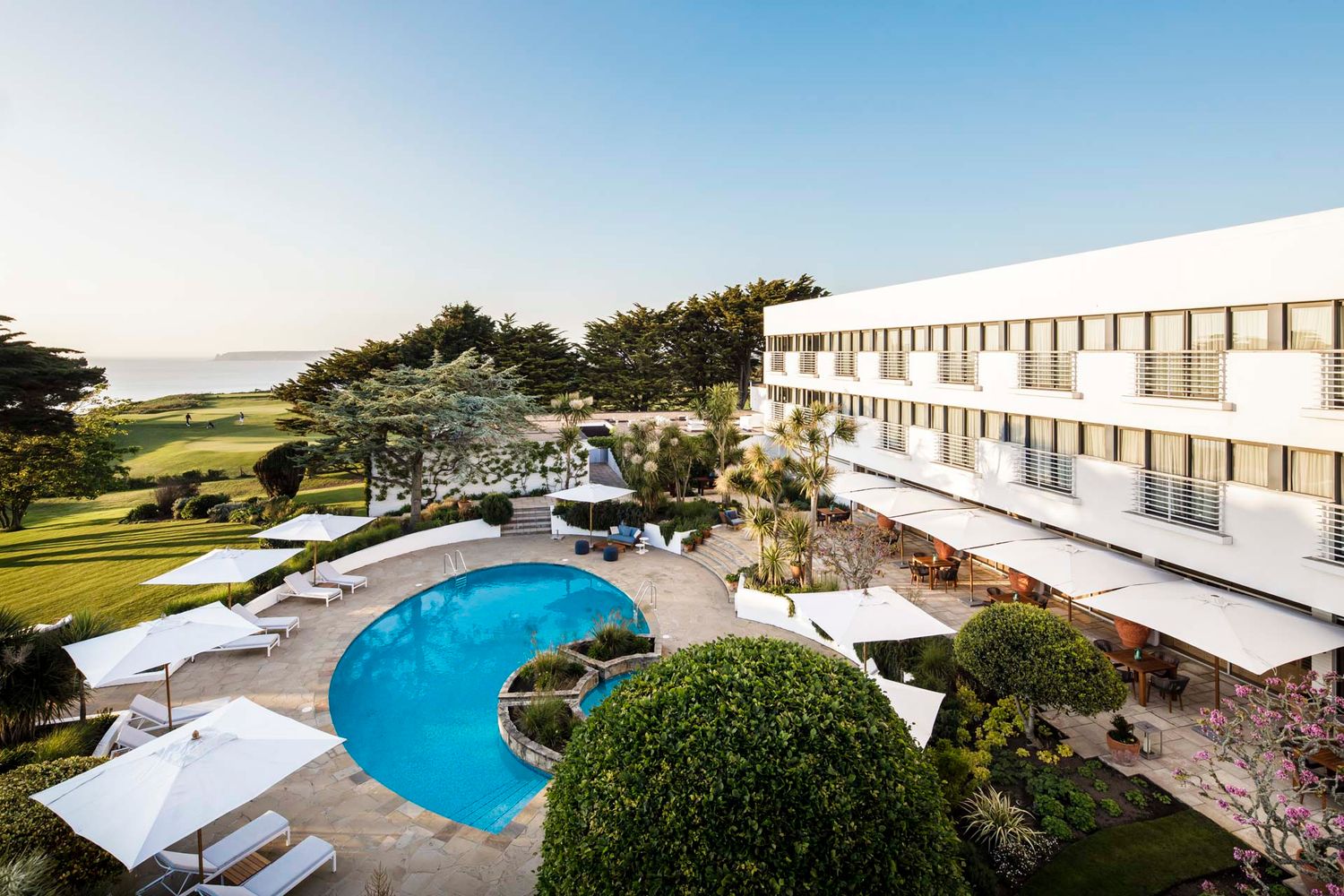 Aerial view of a resort with curved swimming pool and ocean views.