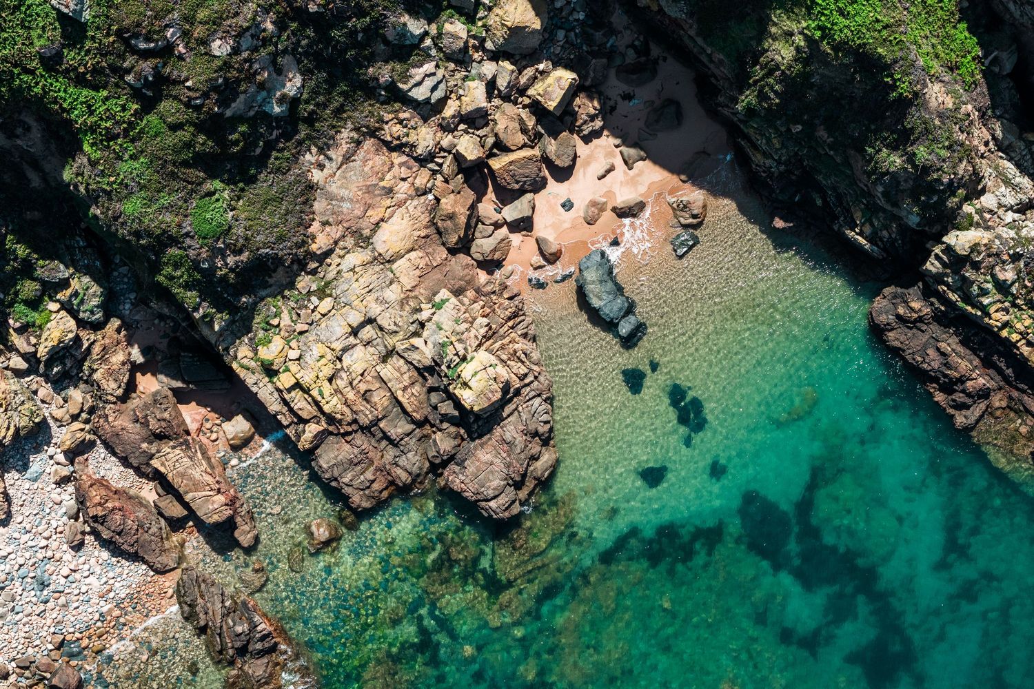 Aerial view of rocky coastline with crystal clear turquoise water and rocky outcrops.