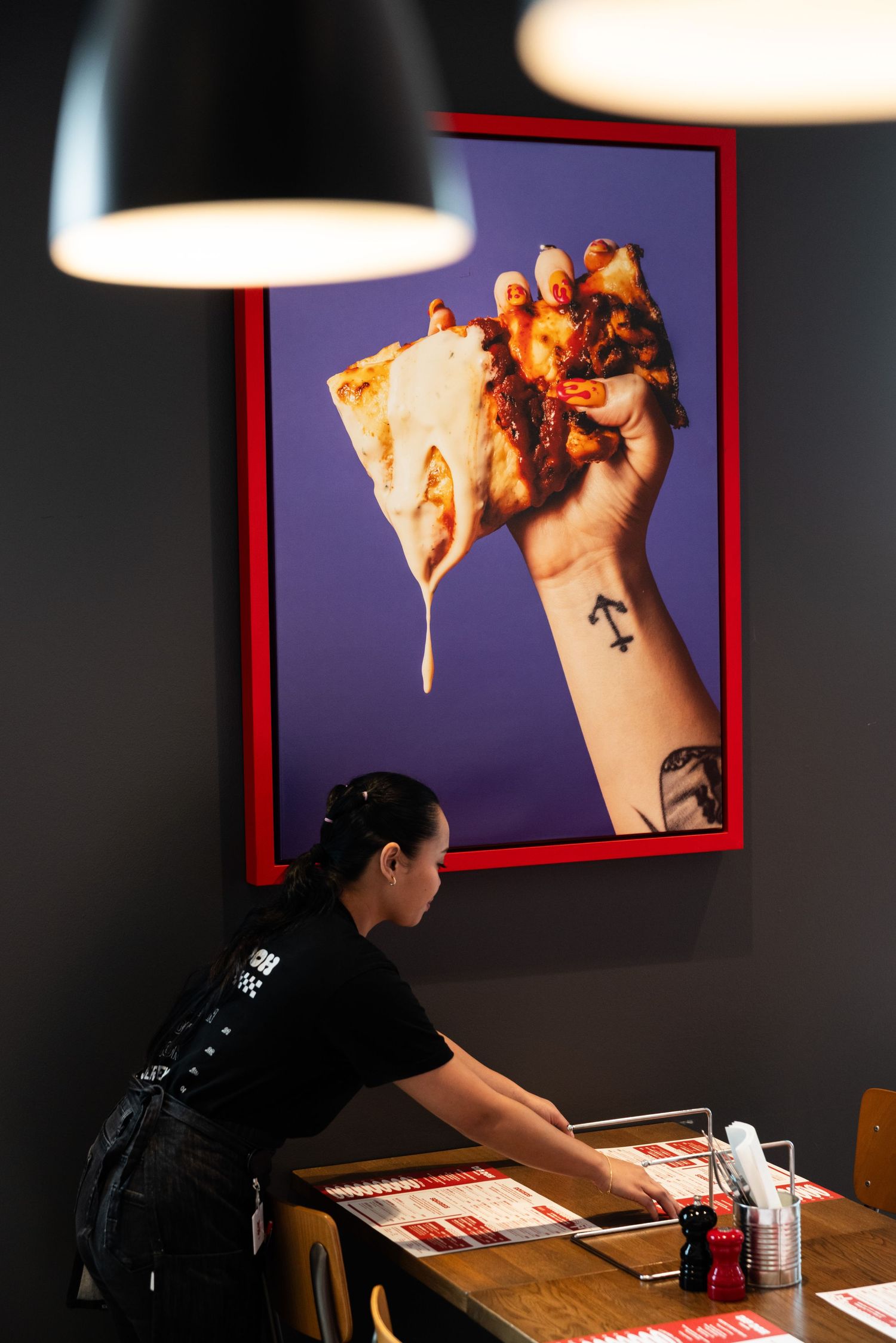Pizza being served on a wooden table in a dimly lit restaurant setting.