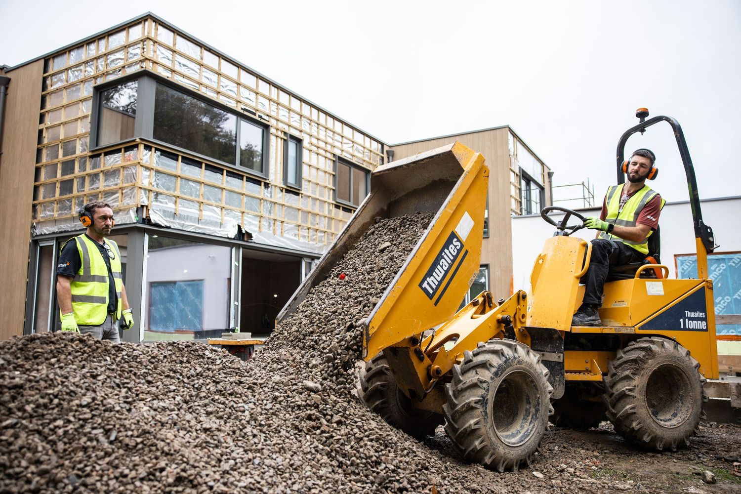 Yellow construction dumper trucks moving gravel at a building site.