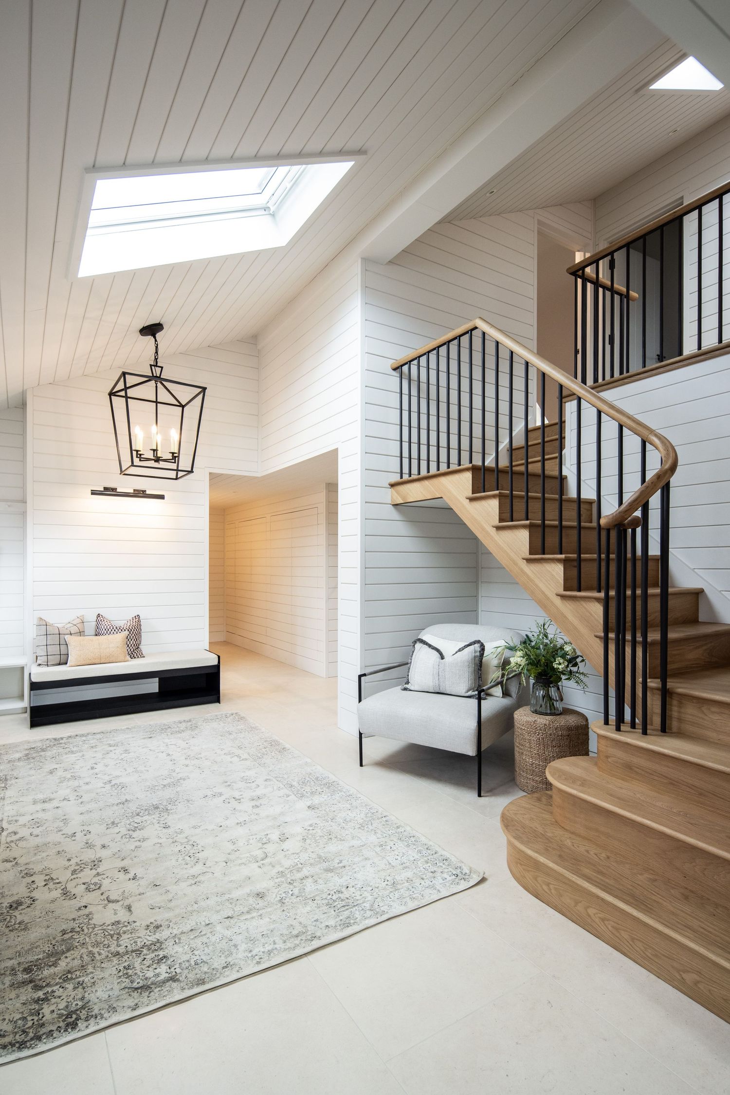 Bright white basement stairway with black metal railings and hardwood steps.