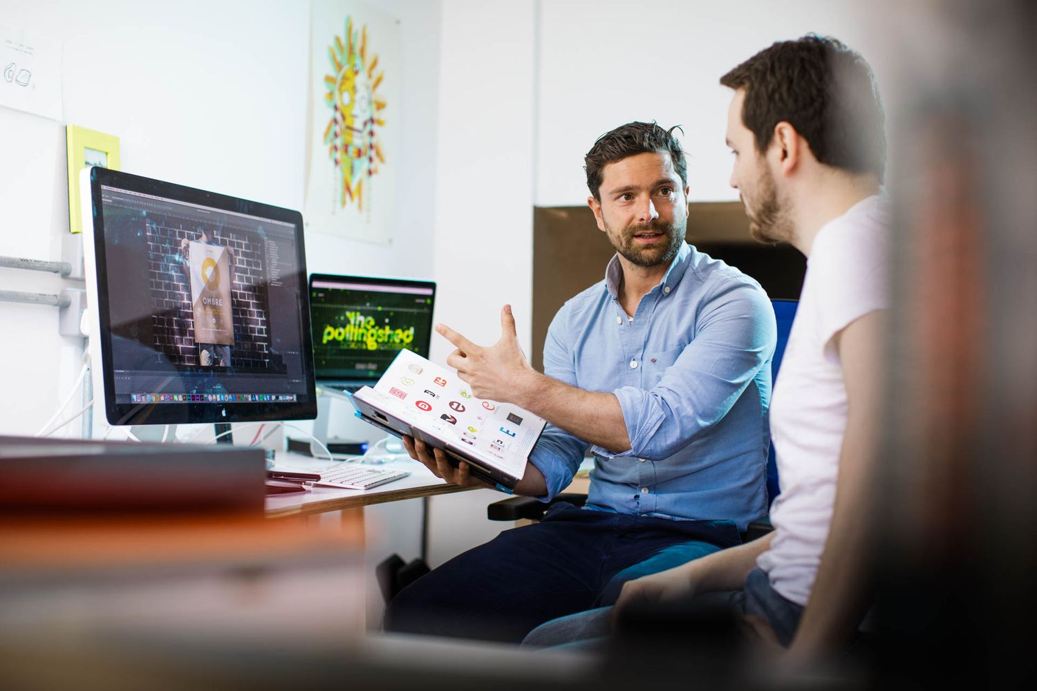 Business professionals collaborating while reviewing content on computer screens in modern office setting.