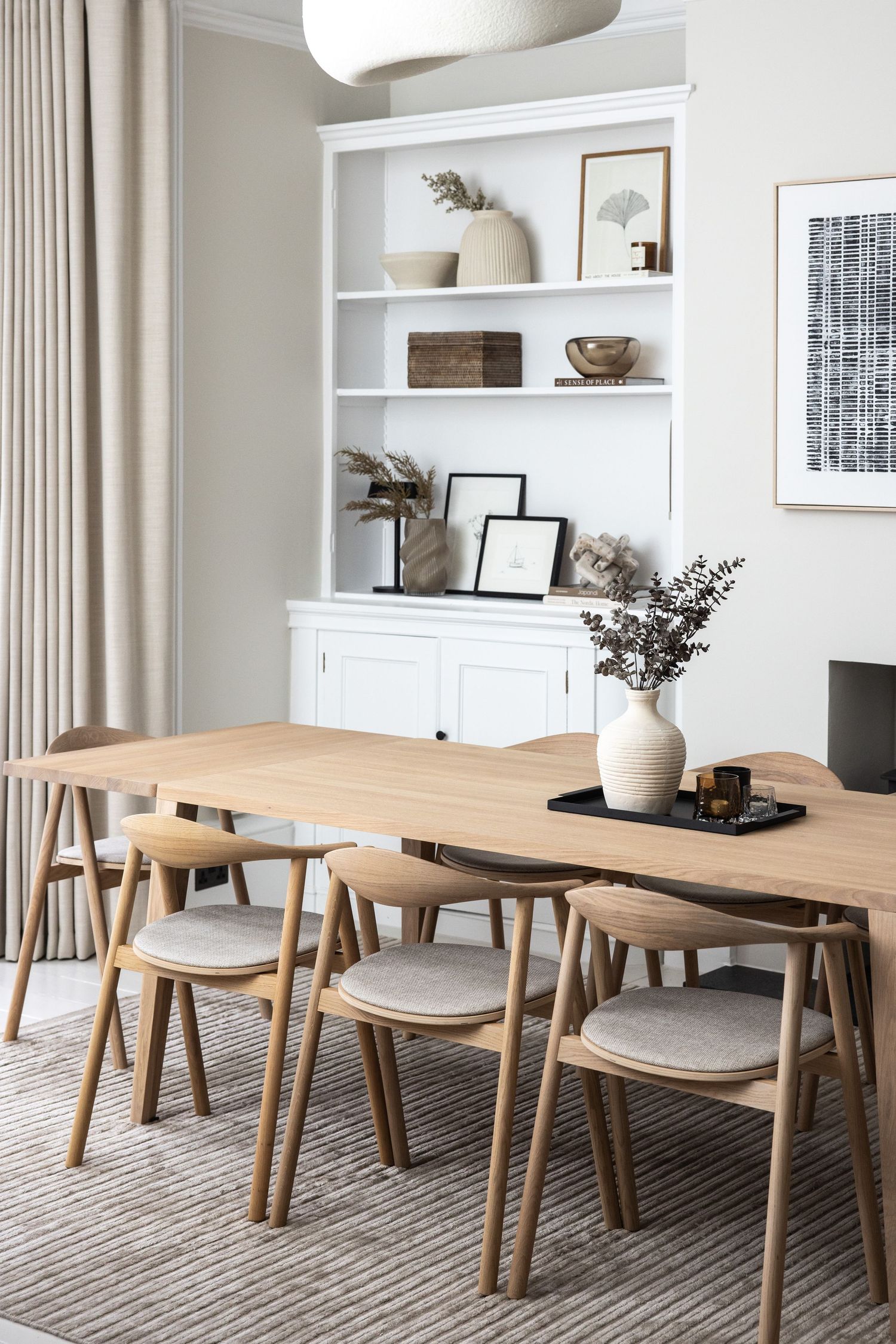 Modern dining room with wooden table, chairs and built-in white shelving units.