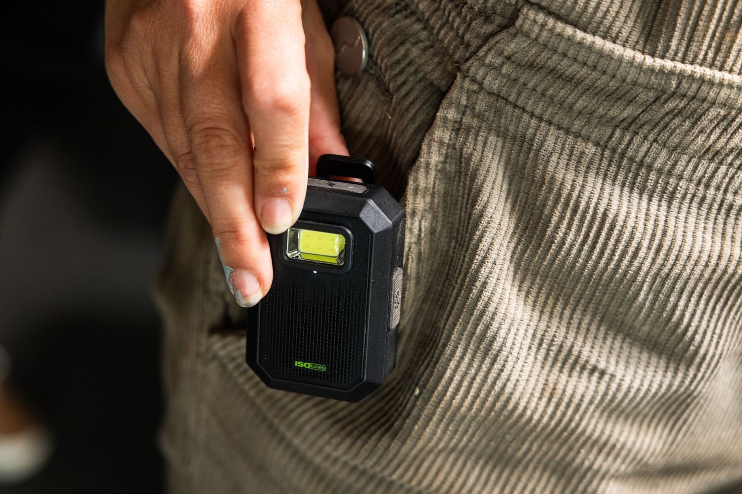 Hand holding small electronic measuring device in pocket.
