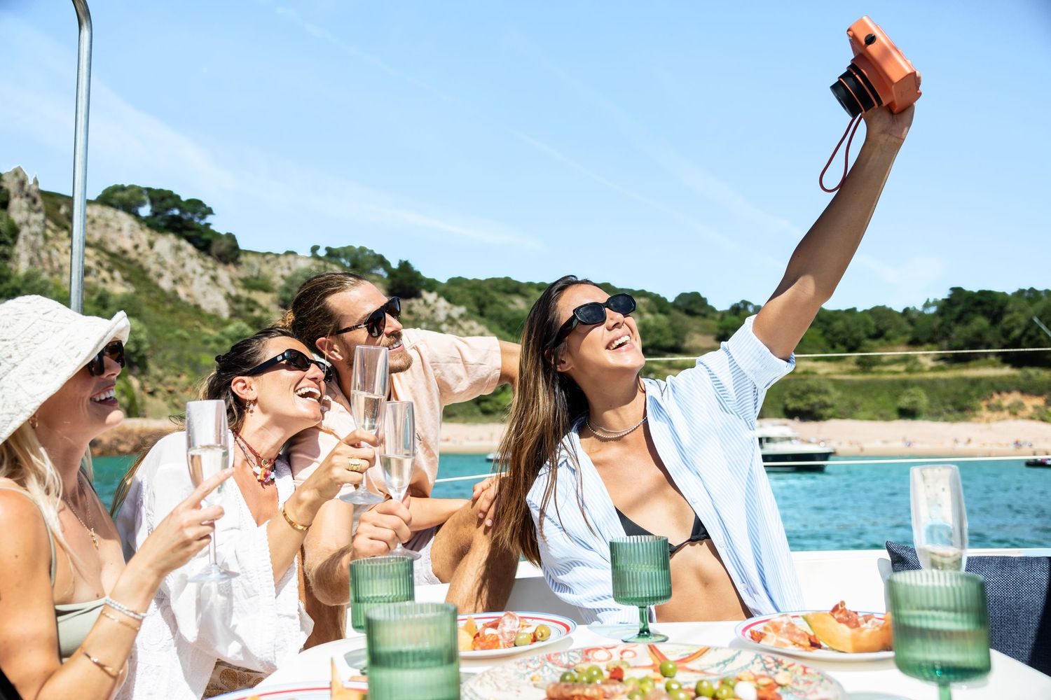 Group enjoying drinks and snacks at an outdoor party by the water.