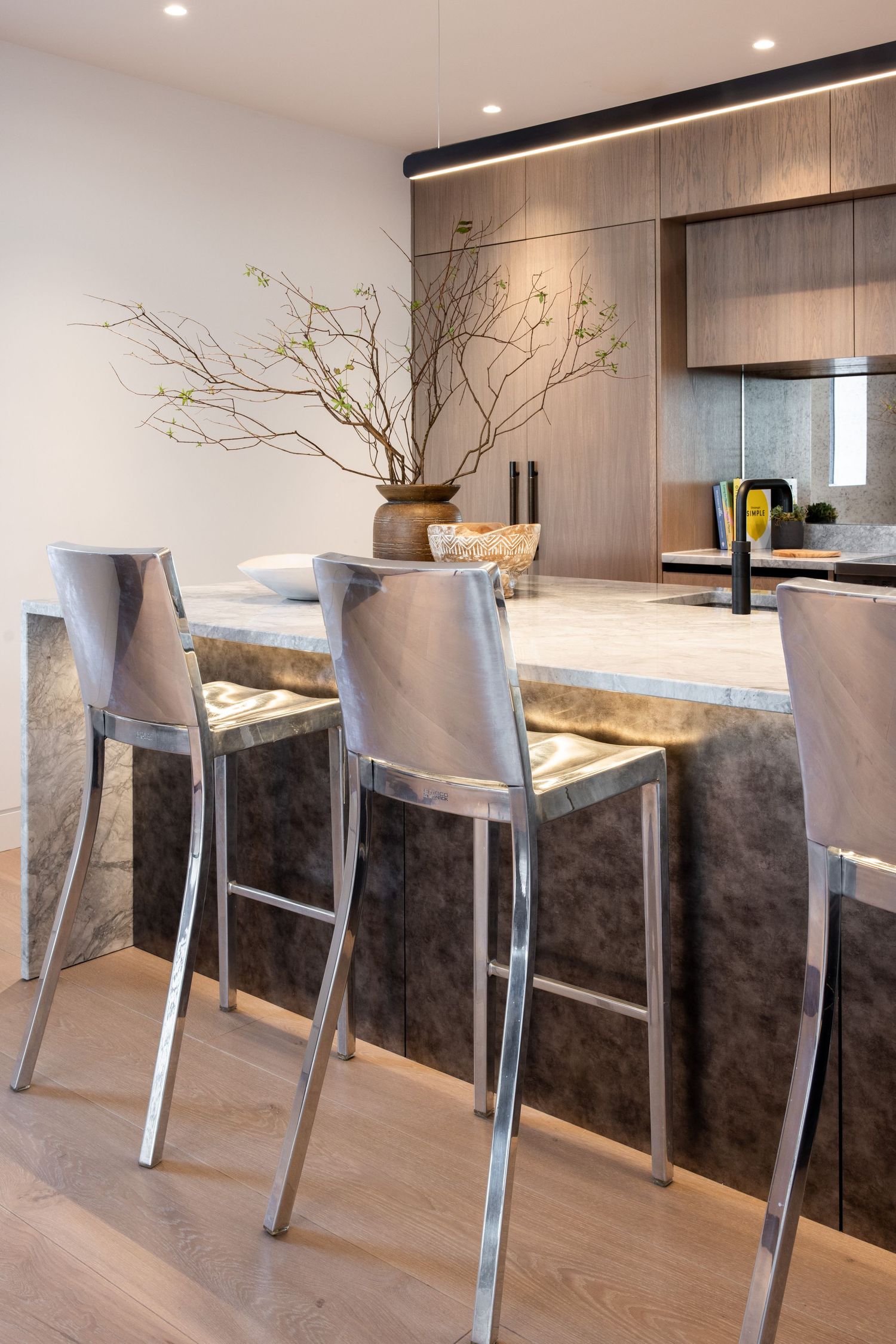 Contemporary kitchen bar with metallic stools and dramatic marble waterfall countertop.