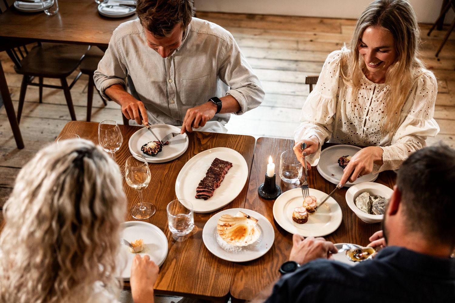 Group enjoying a casual dinner gathering at a rustic wooden table in warm lighting.