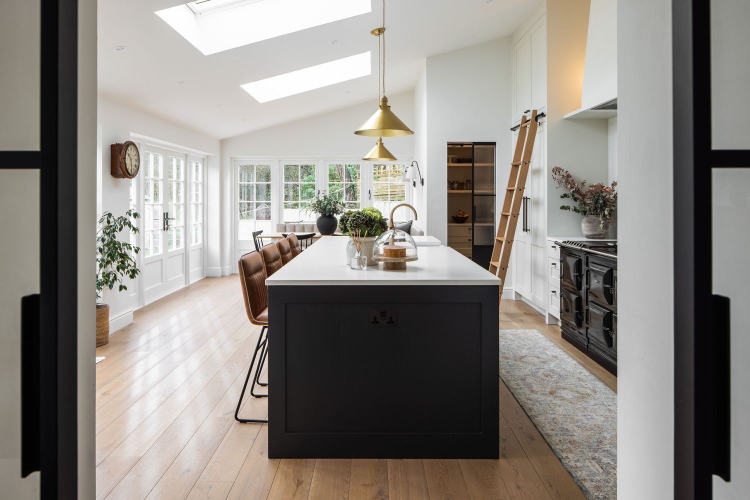 Modern bright kitchen with skylight features black island, hardwood floors and white cabinetry.