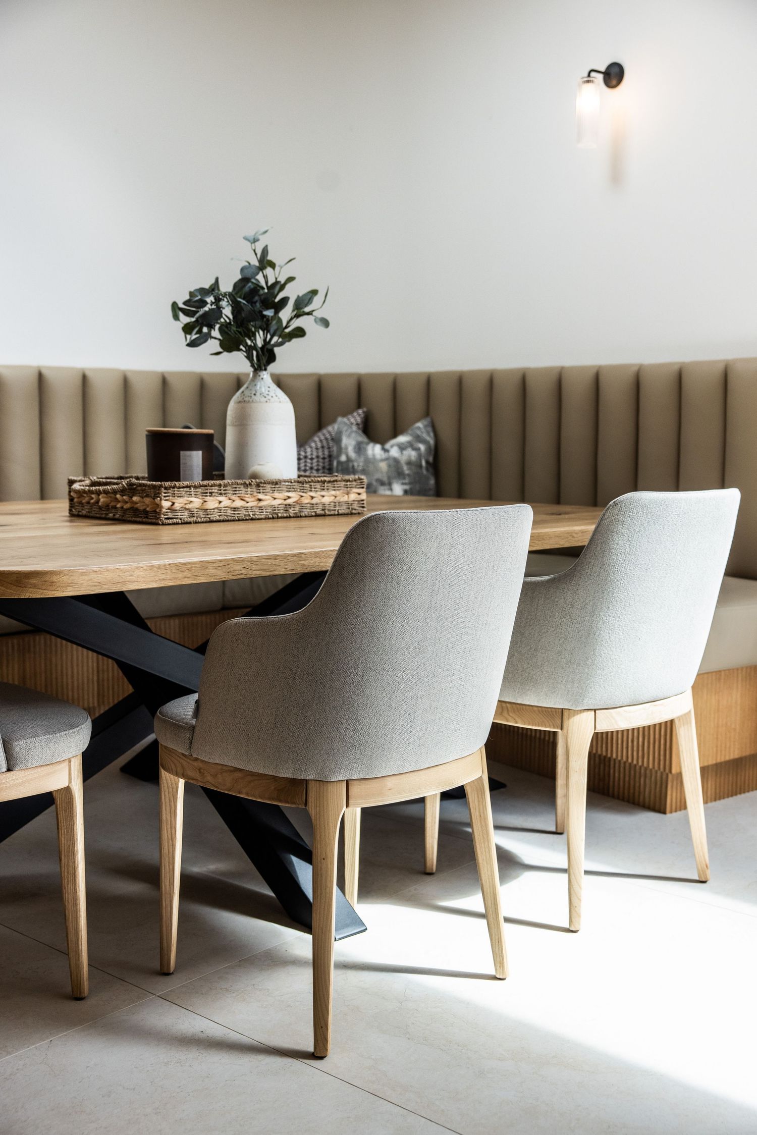 Modern dining setup with upholstered bench seating and contemporary chairs around a wooden table.