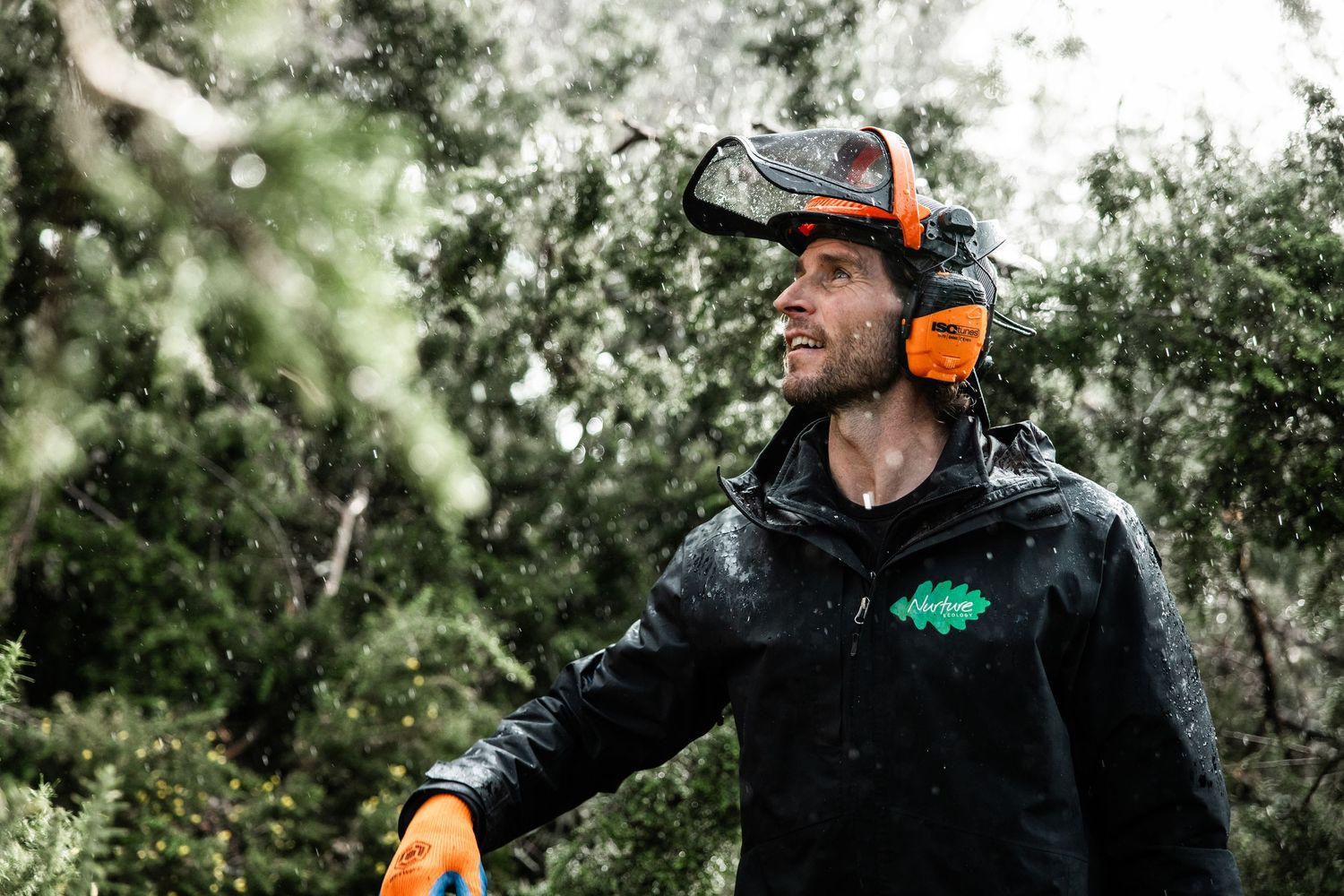 Forest worker wearing protective gear and ear protection during outdoor work.