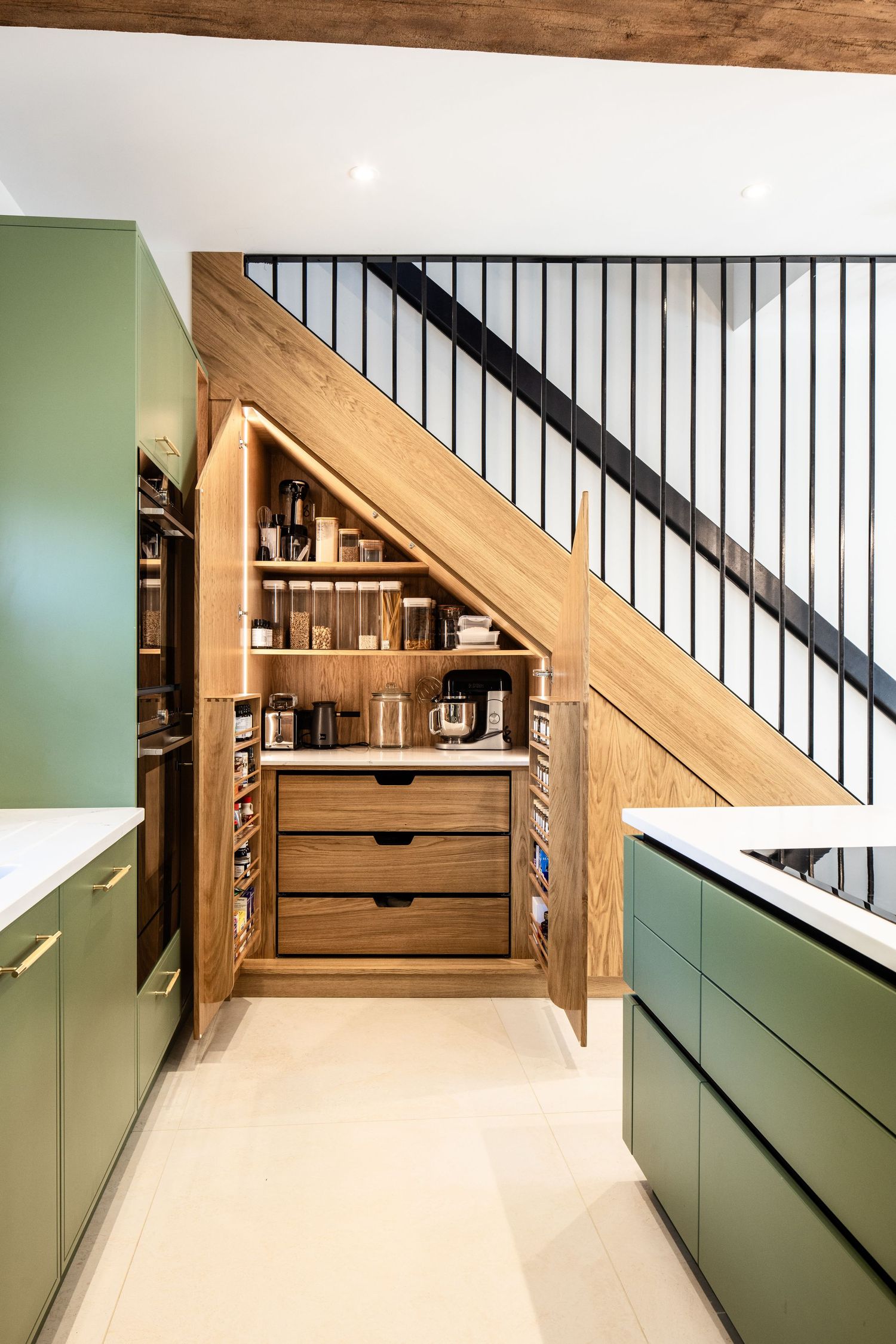 Custom under-stair storage solution with green cabinets and wooden details.