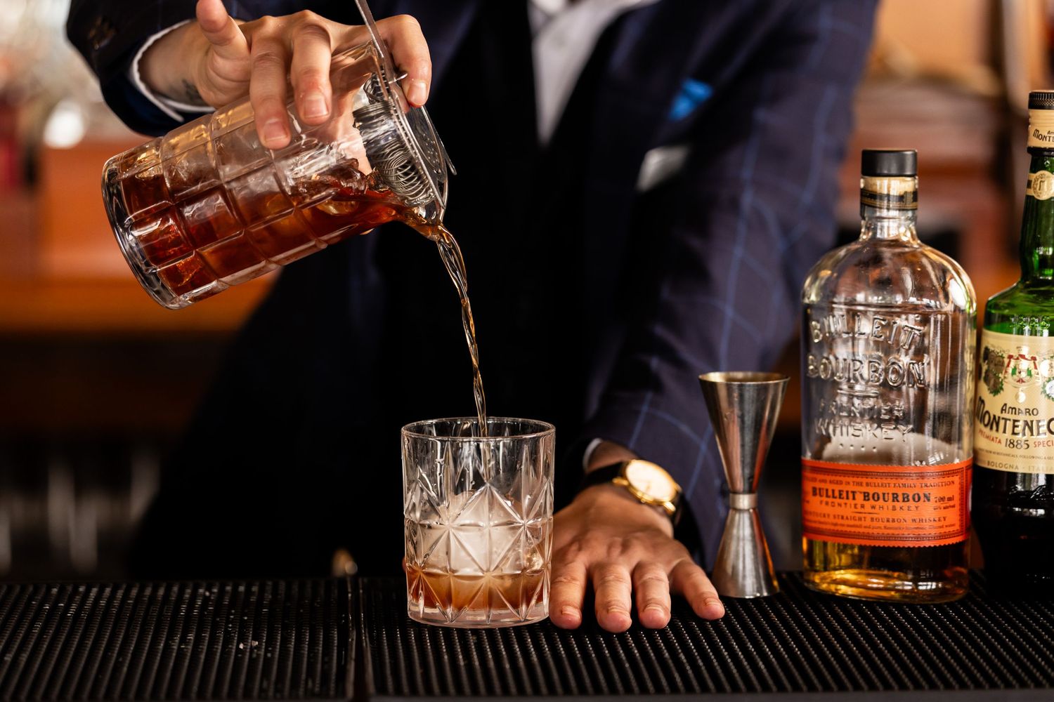 Close-up shots of premium whiskey bottles and cocktail preparation at a bar.