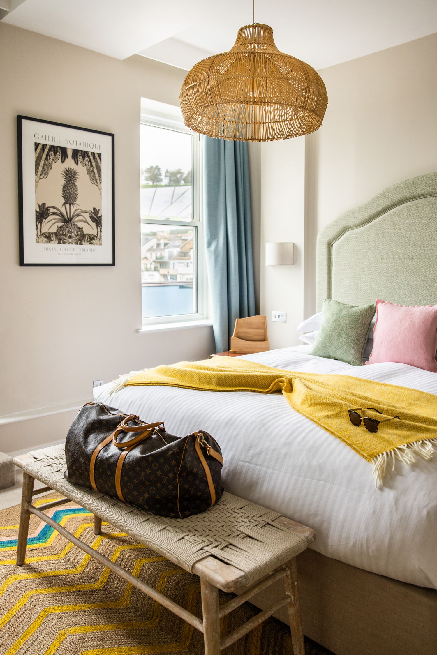 Modern bedroom interior with rattan pendant lights and yellow accents featuring coastal decor.
