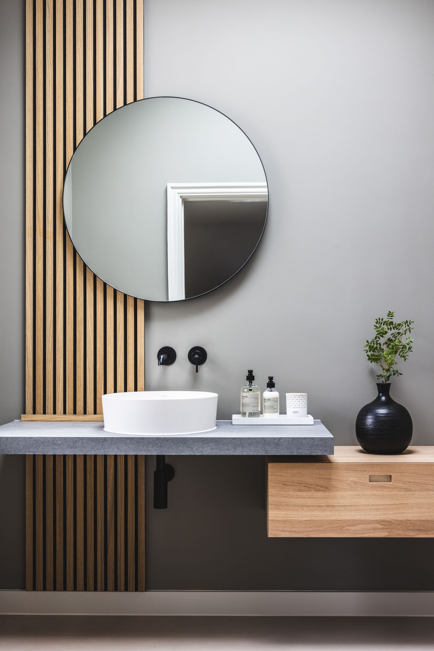 Modern bathroom vanity with round mirror, wooden accents, and minimalist design elements.