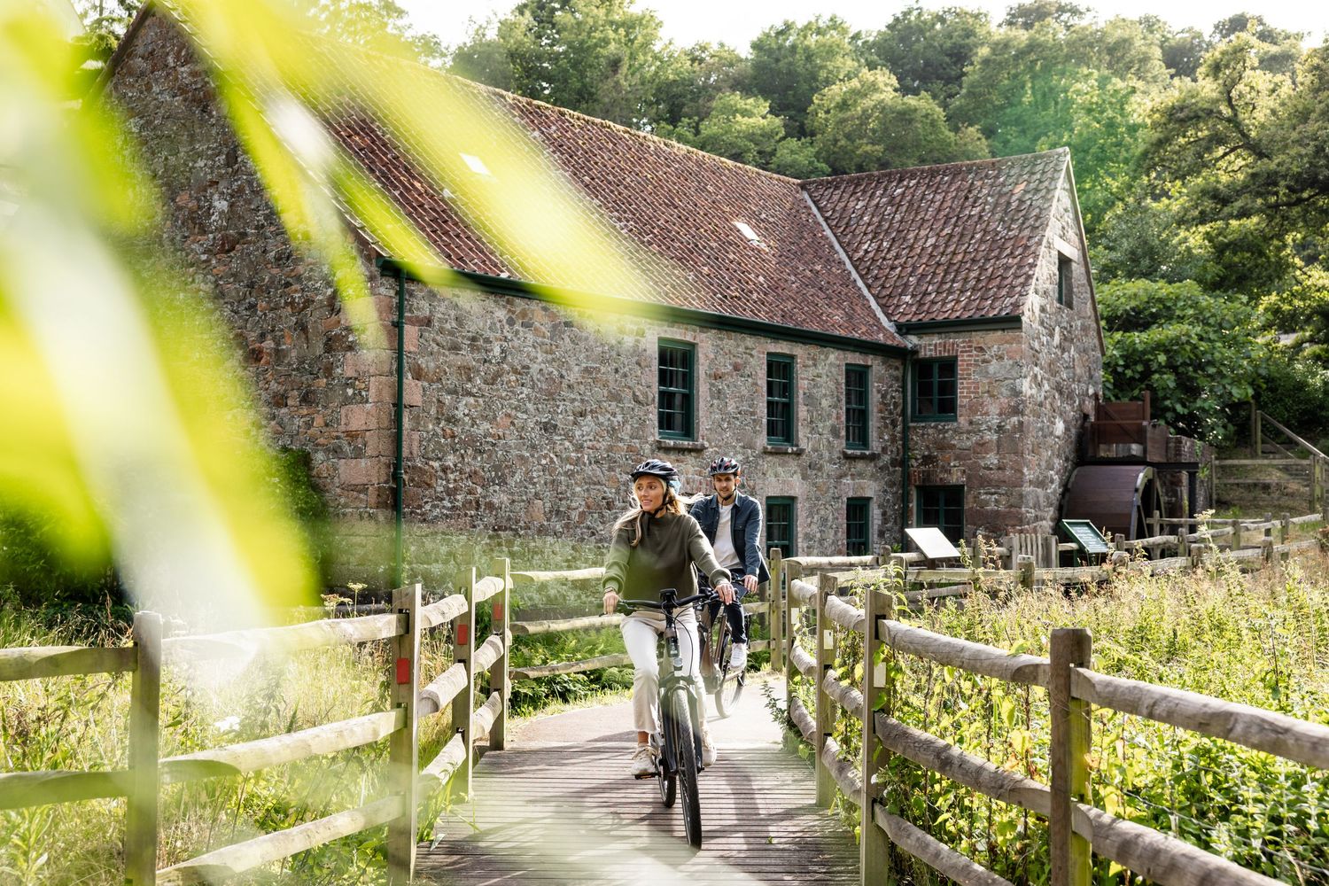 Stone pathway leading to rustic countryside buildings surrounded by green gardens.