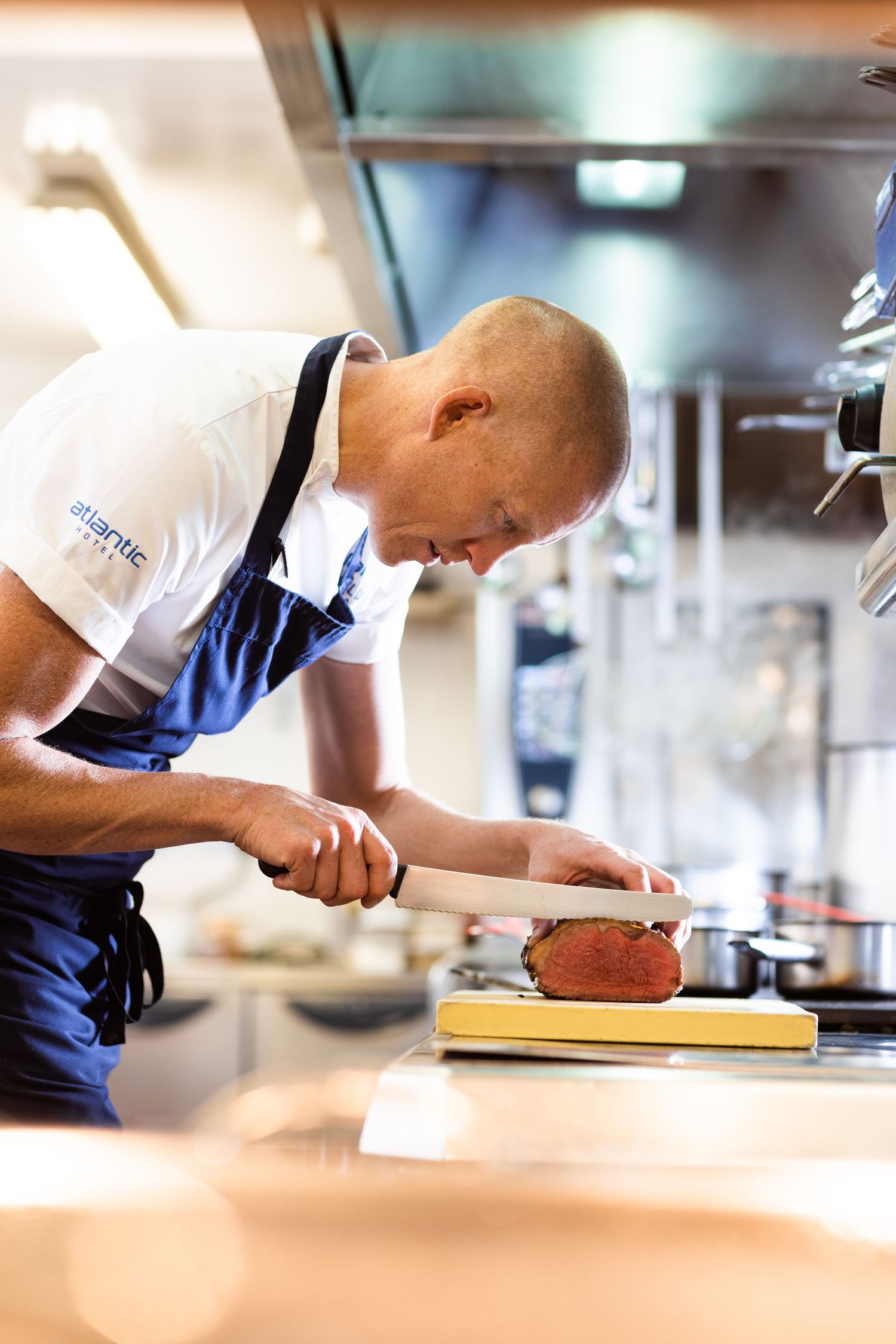 Chef carefully preparing ingredients on a wooden cutting board in a commercial kitchen.
