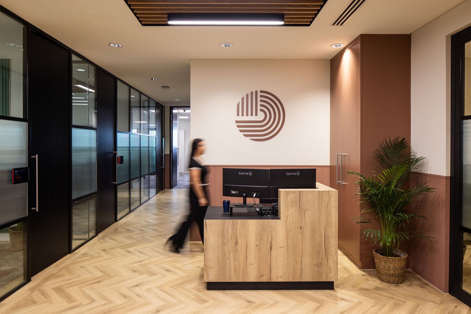 Modern office reception area with wooden desk and minimalist circular logo on wall.