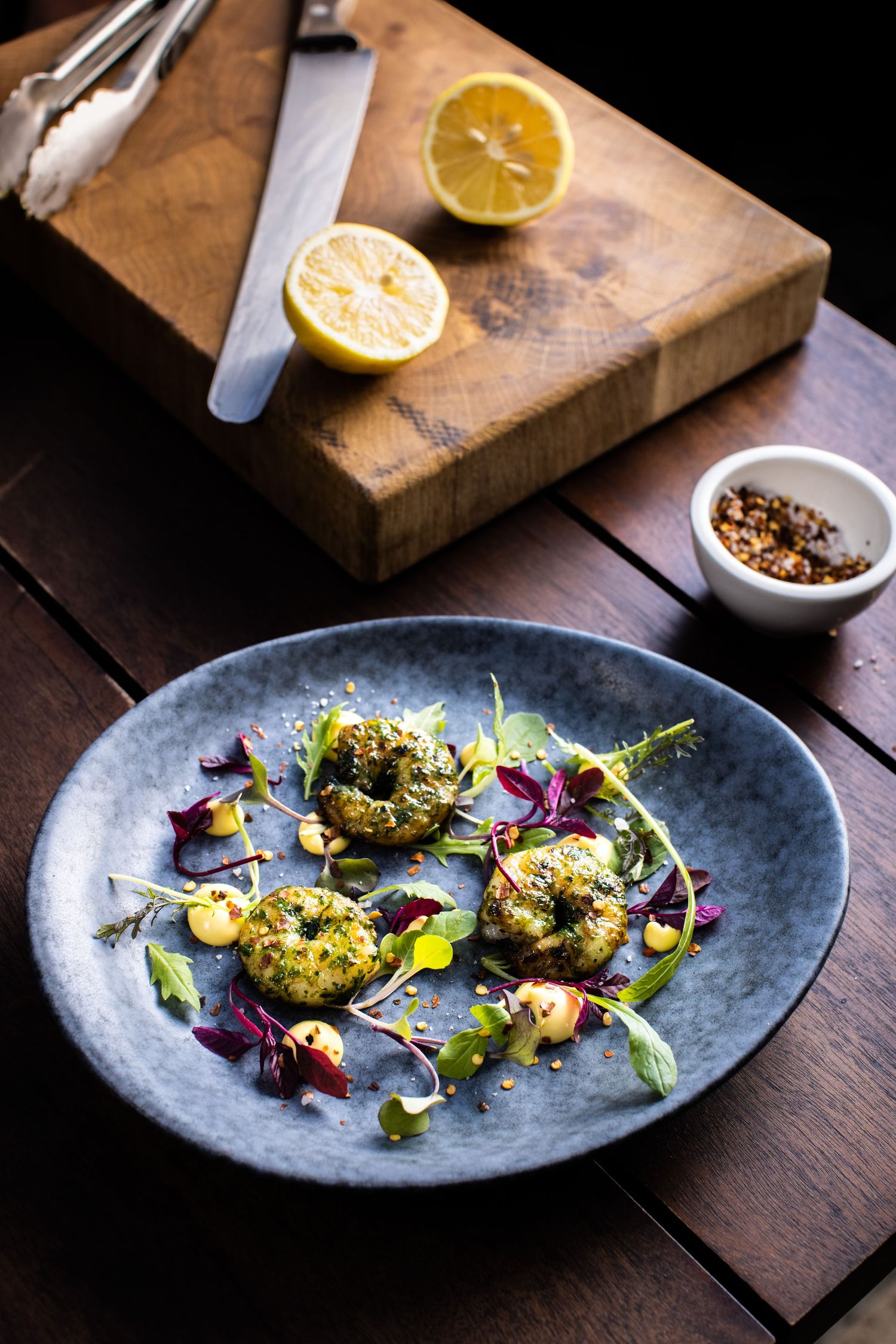 Beautifully plated gourmet dish with microgreens and citrus on a blue ceramic plate.