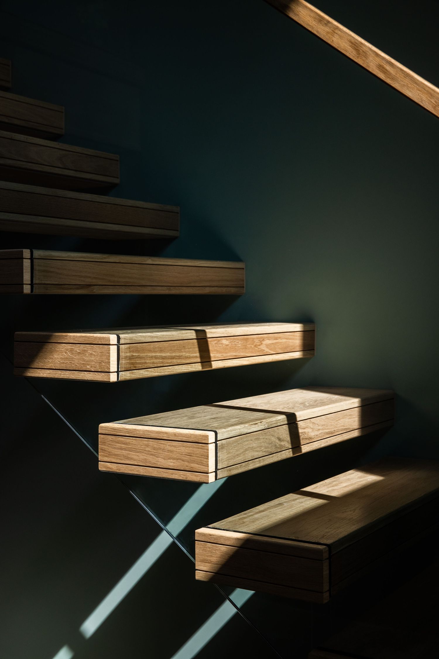 Modern floating wooden staircase design with minimalist X-shaped metal supports in dramatic lighting.