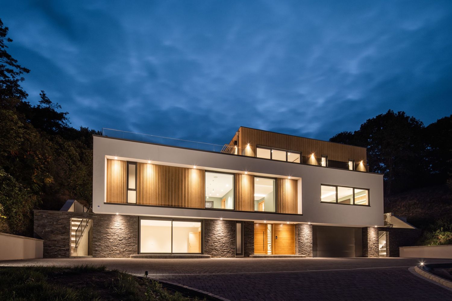 Modern luxury home with illuminated exterior glows against dusky blue evening sky.