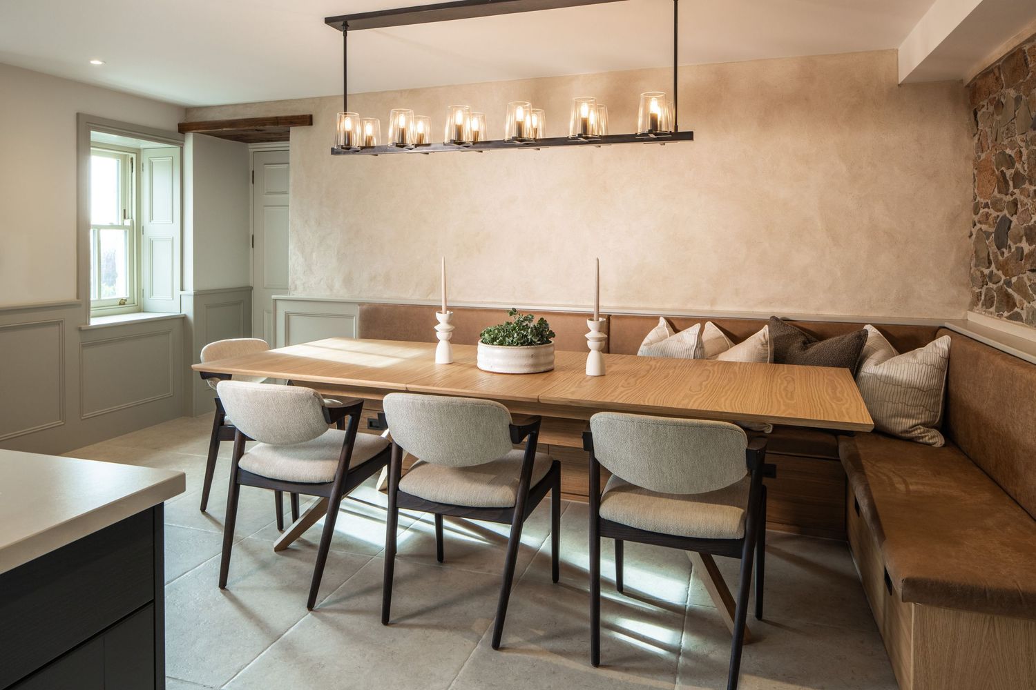 Elegant dining room with long wooden table, bench seating, and modern pendant lighting.