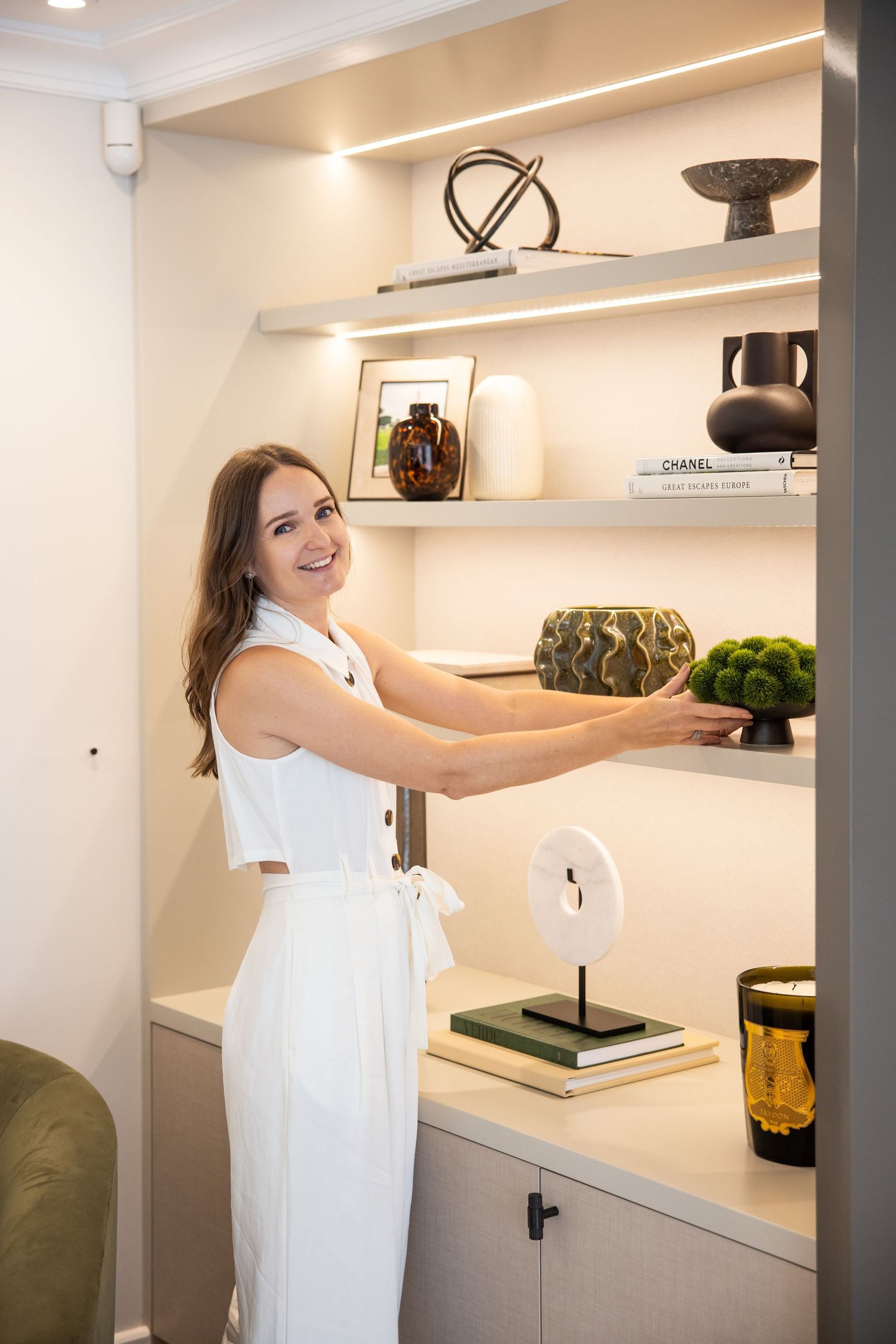 Modern white shelving unit displaying decorative items and greenery.