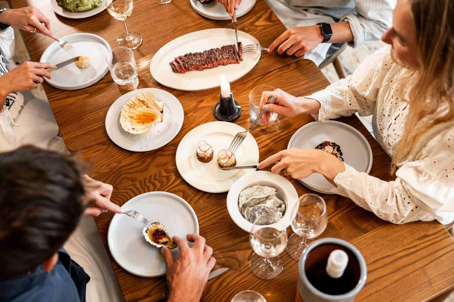Overhead view of friends sharing desserts and drinks at a wooden restaurant table.