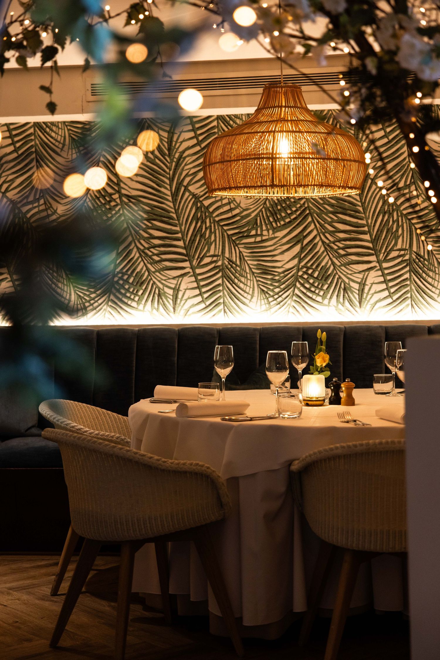 Romantic restaurant interior with woven lamp shades and palm leaf decor creating ambient lighting.