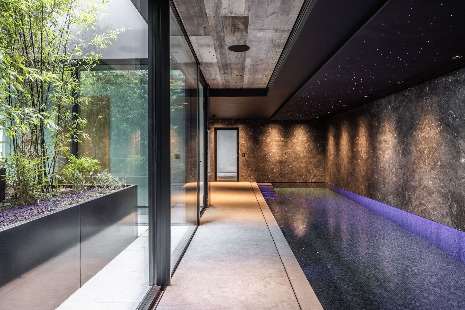 Dramatic corridor with purple LED lighting and glass walls creating a futuristic atmosphere.