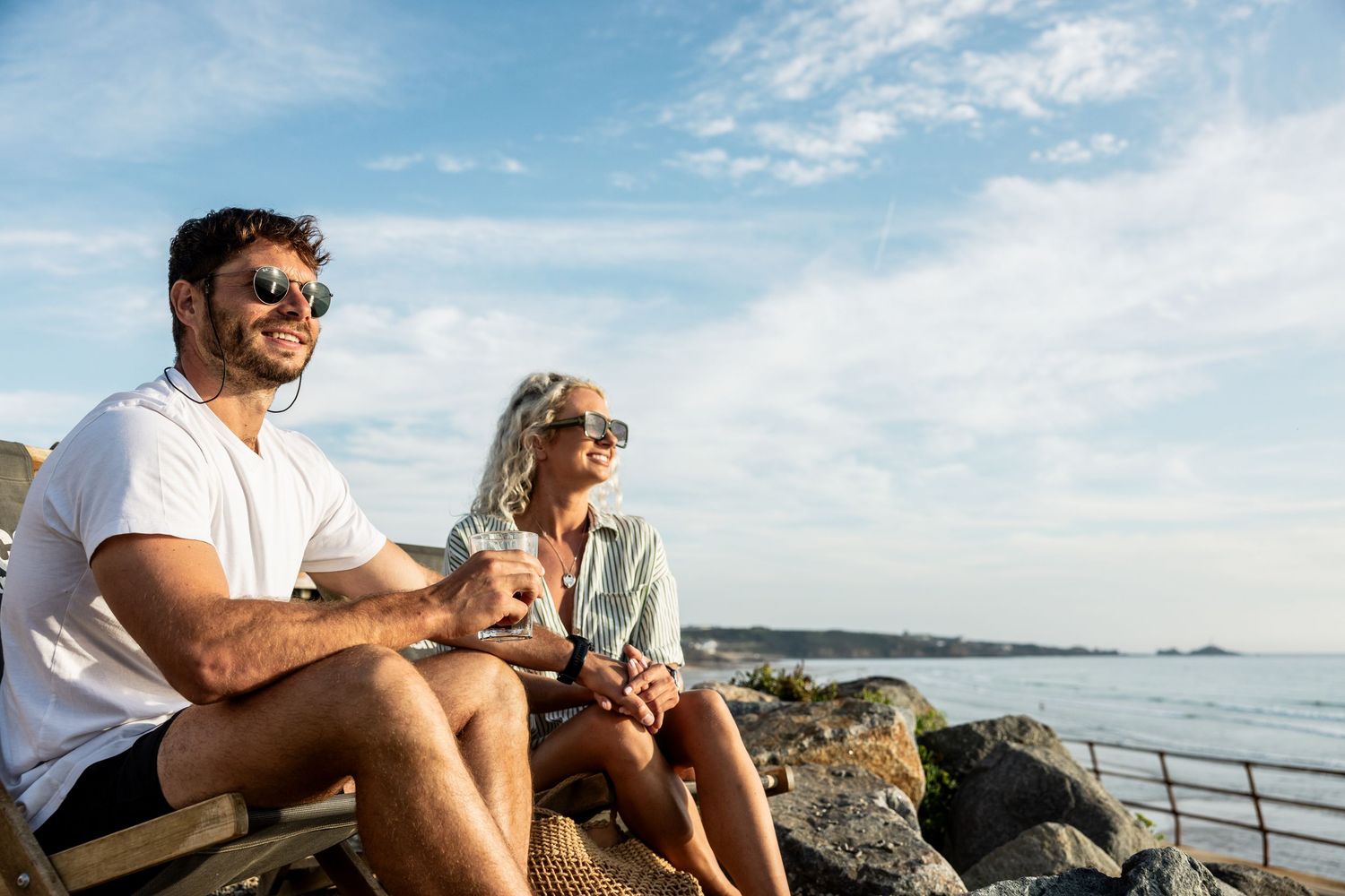 Group enjoying a relaxing day at the beach with views of the ocean and rocky coastline.