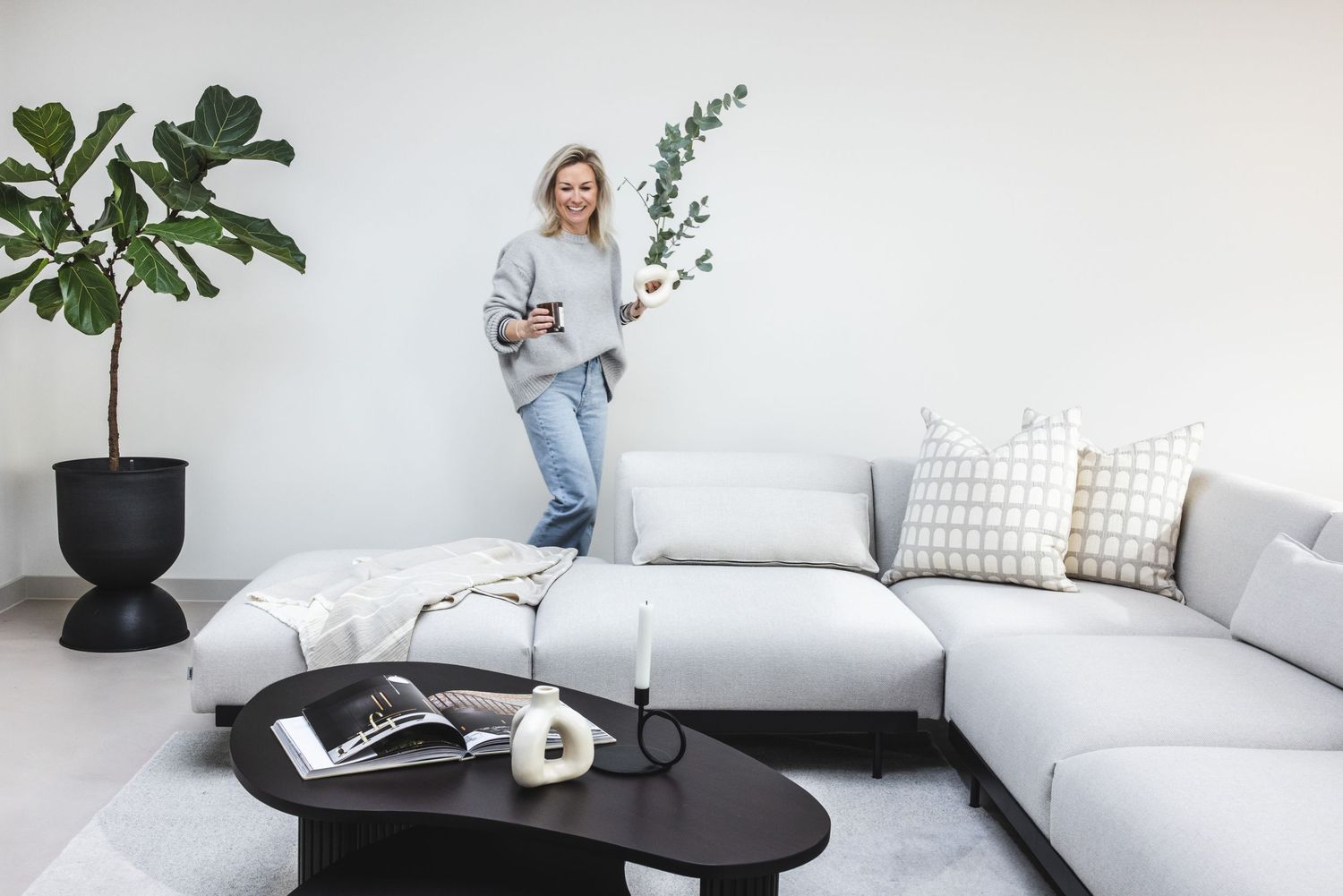 Contemporary living room with white sectional sofa, black coffee table and natural light.