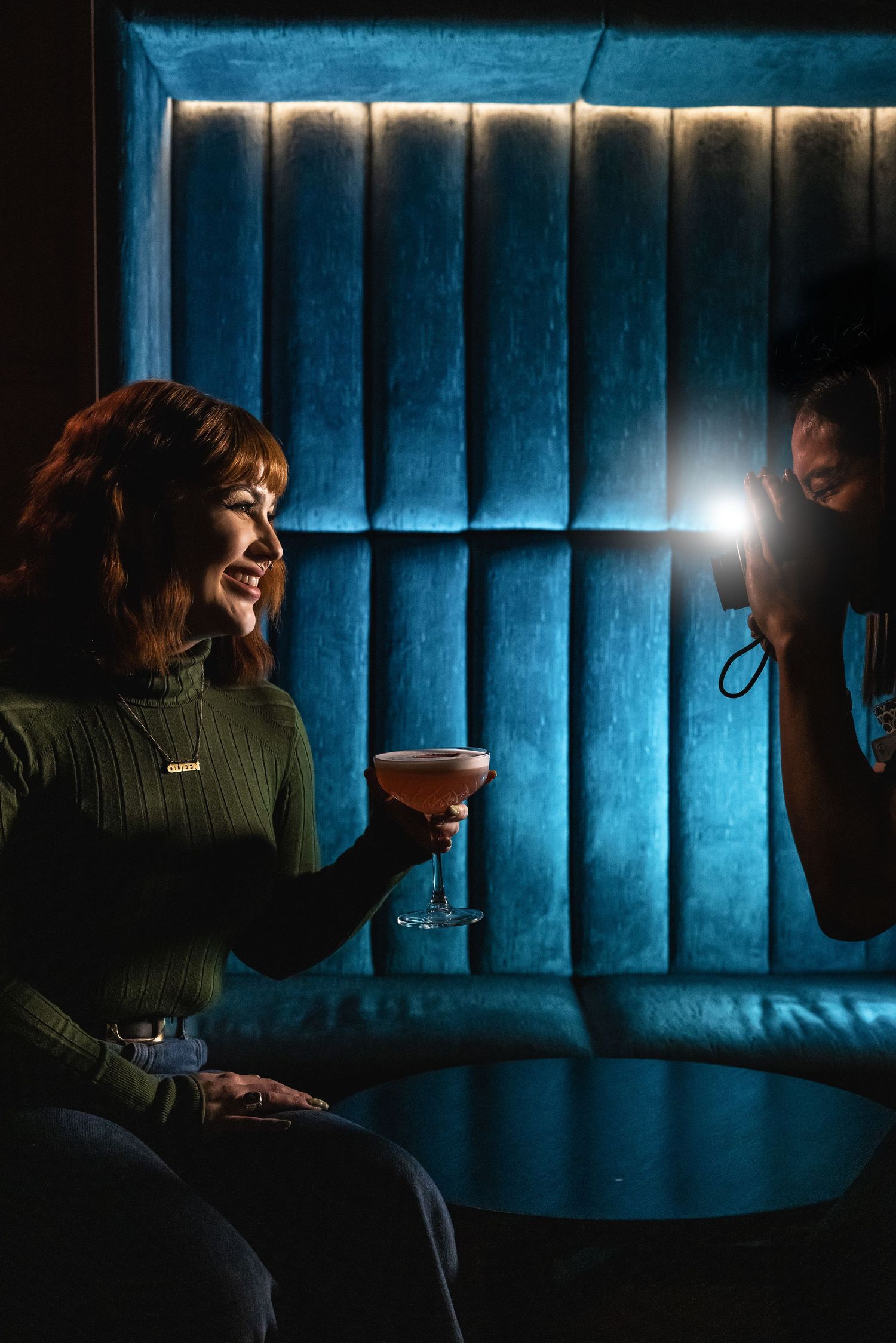 Dramatic blue-lit lounge setting with cocktail photography session.