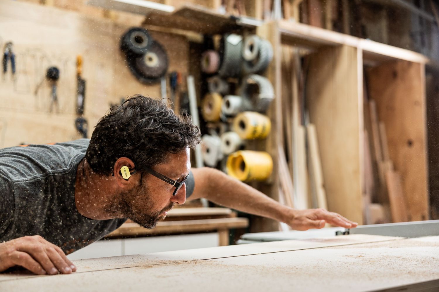 Carpenter examining wooden surface in traditional workshop setting.