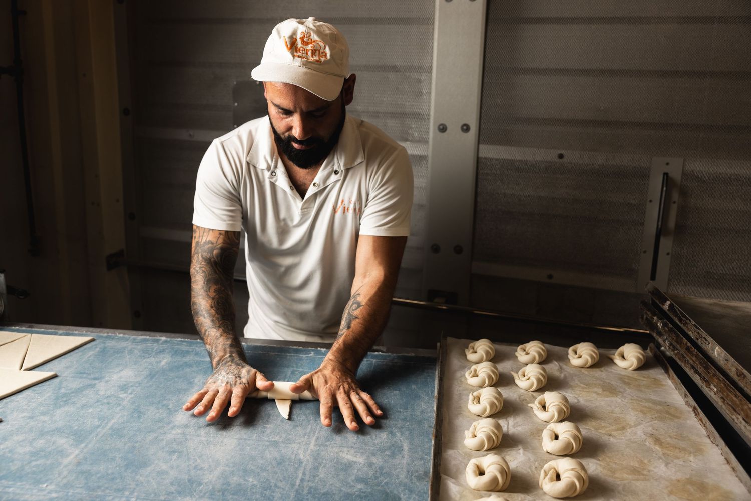 Baker preparing raw dough portions on flour-dusted counter.