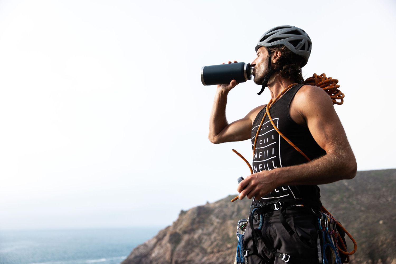 Athletic cyclist taking a drink break while mountain biking against scenic backdrop.