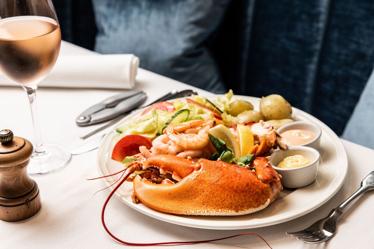 Gourmet seafood dishes plated on white dishes against a dark background.