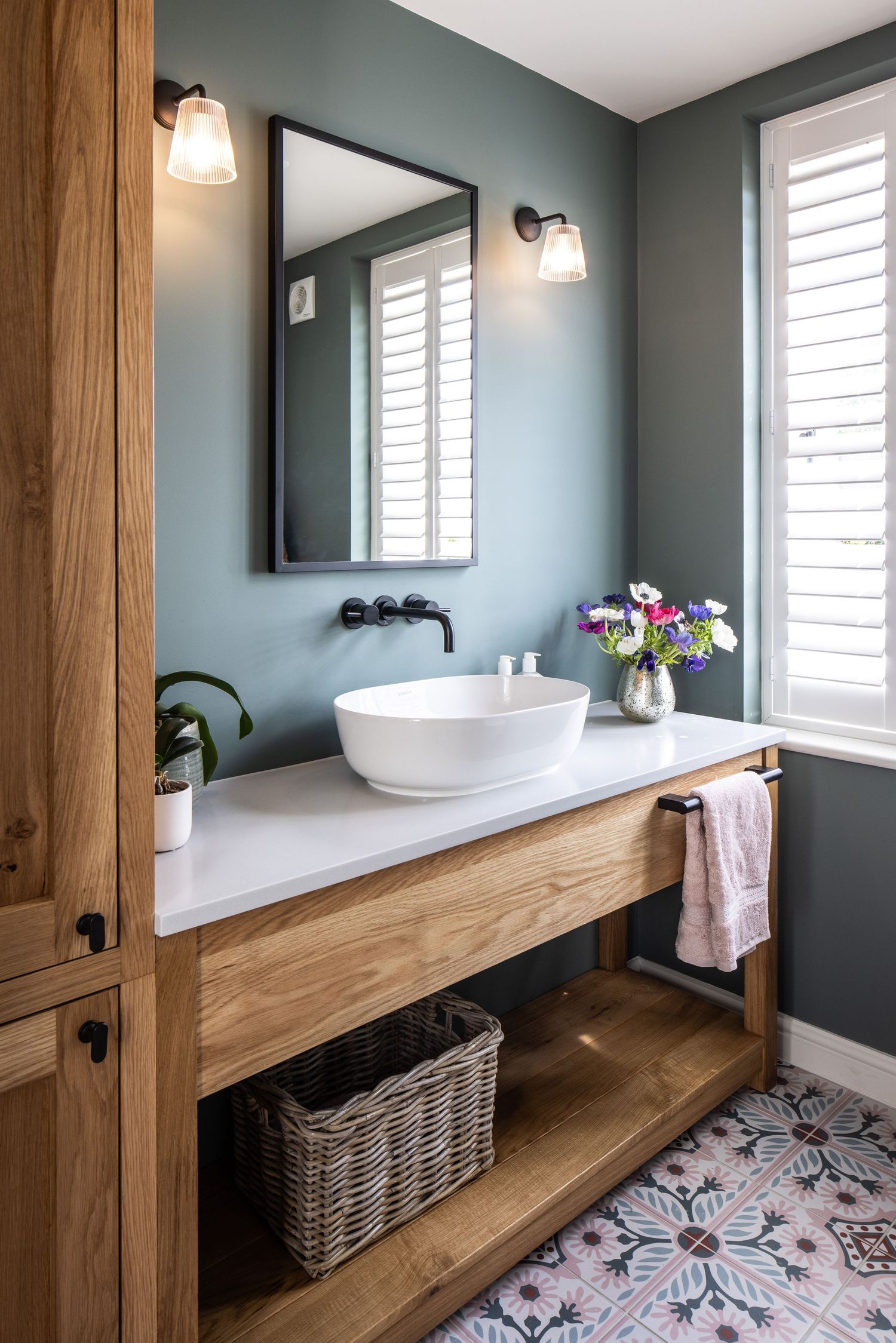 Modern bathroom featuring a floating wood vanity, vessel sink, and patterned floor tiles in sage green tones.