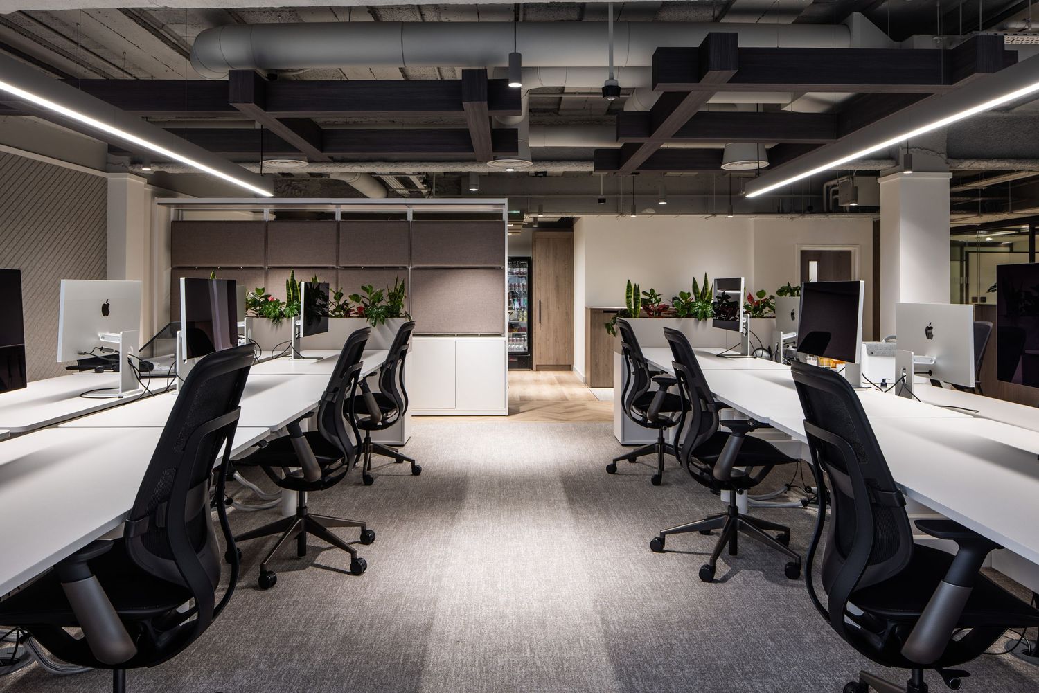 Spacious office area with black ergonomic chairs and exposed industrial ceiling design.