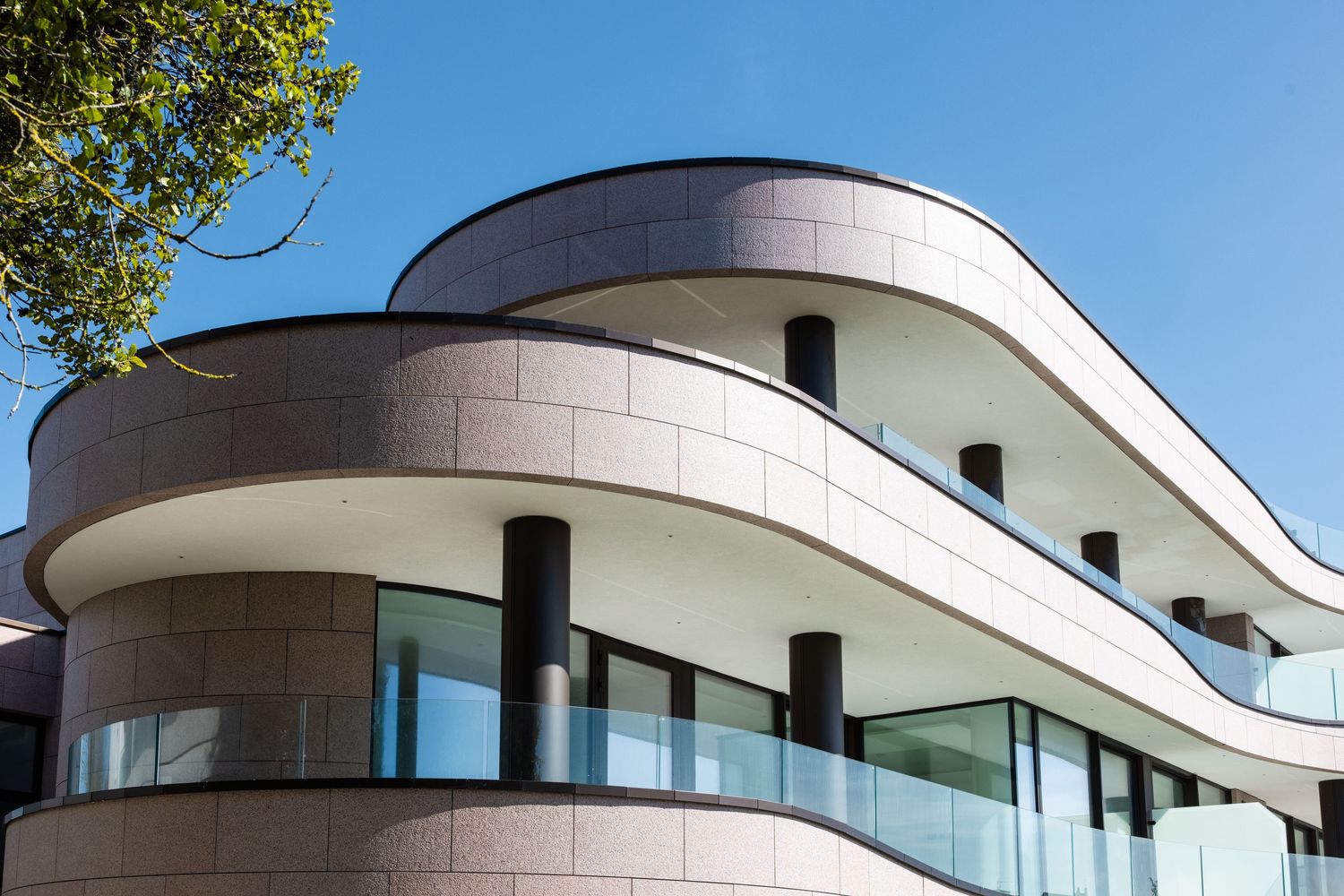 Contemporary building exterior featuring flowing curved design and expansive glass windows.