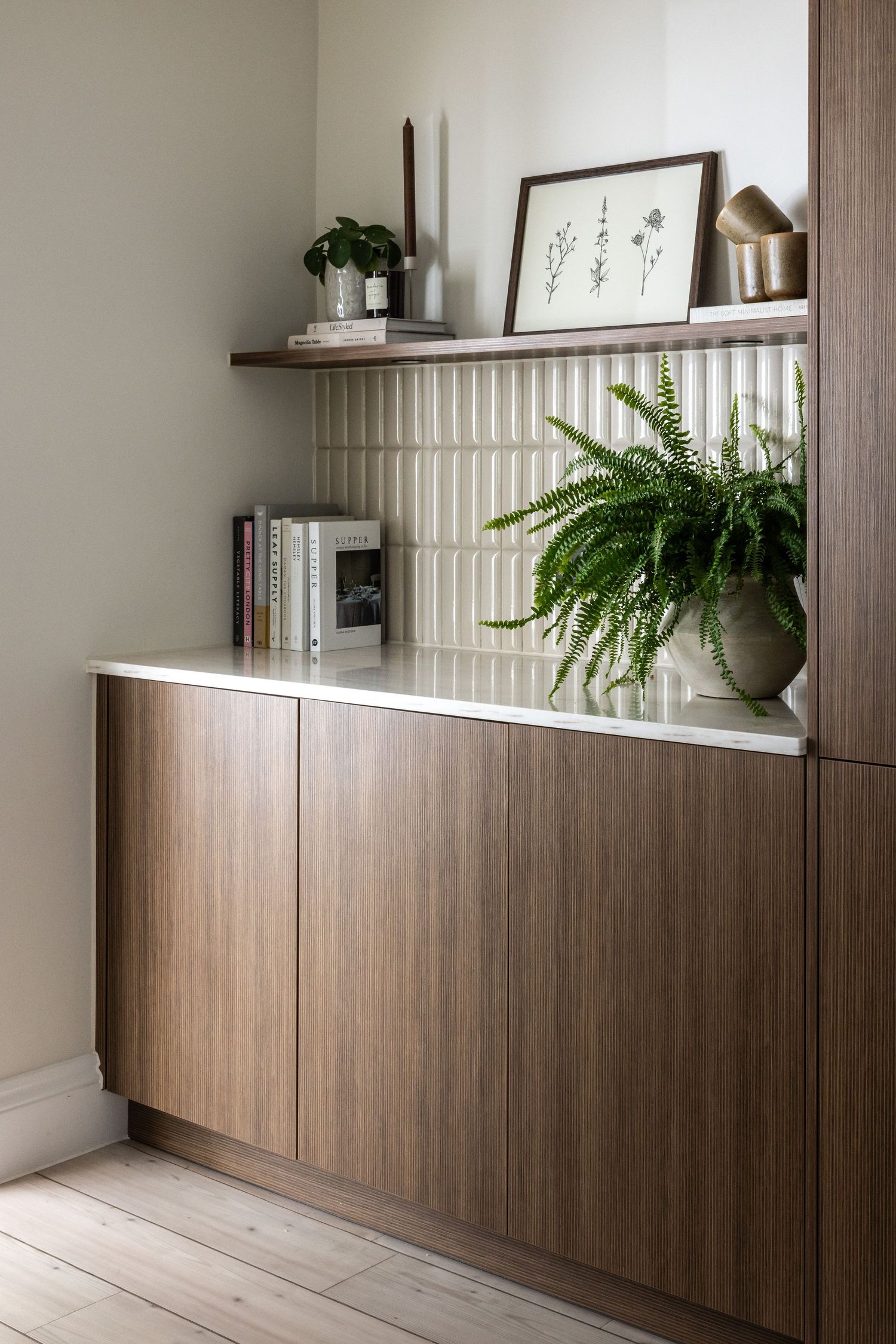 Modern wooden storage cabinets with sleek paneling and built-in shelving create a minimalist hallway design with potted ferns.