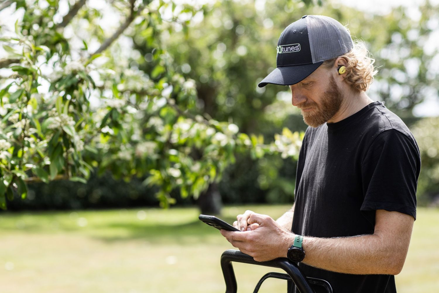 Workers checking mobile devices while wearing safety gear outdoors.